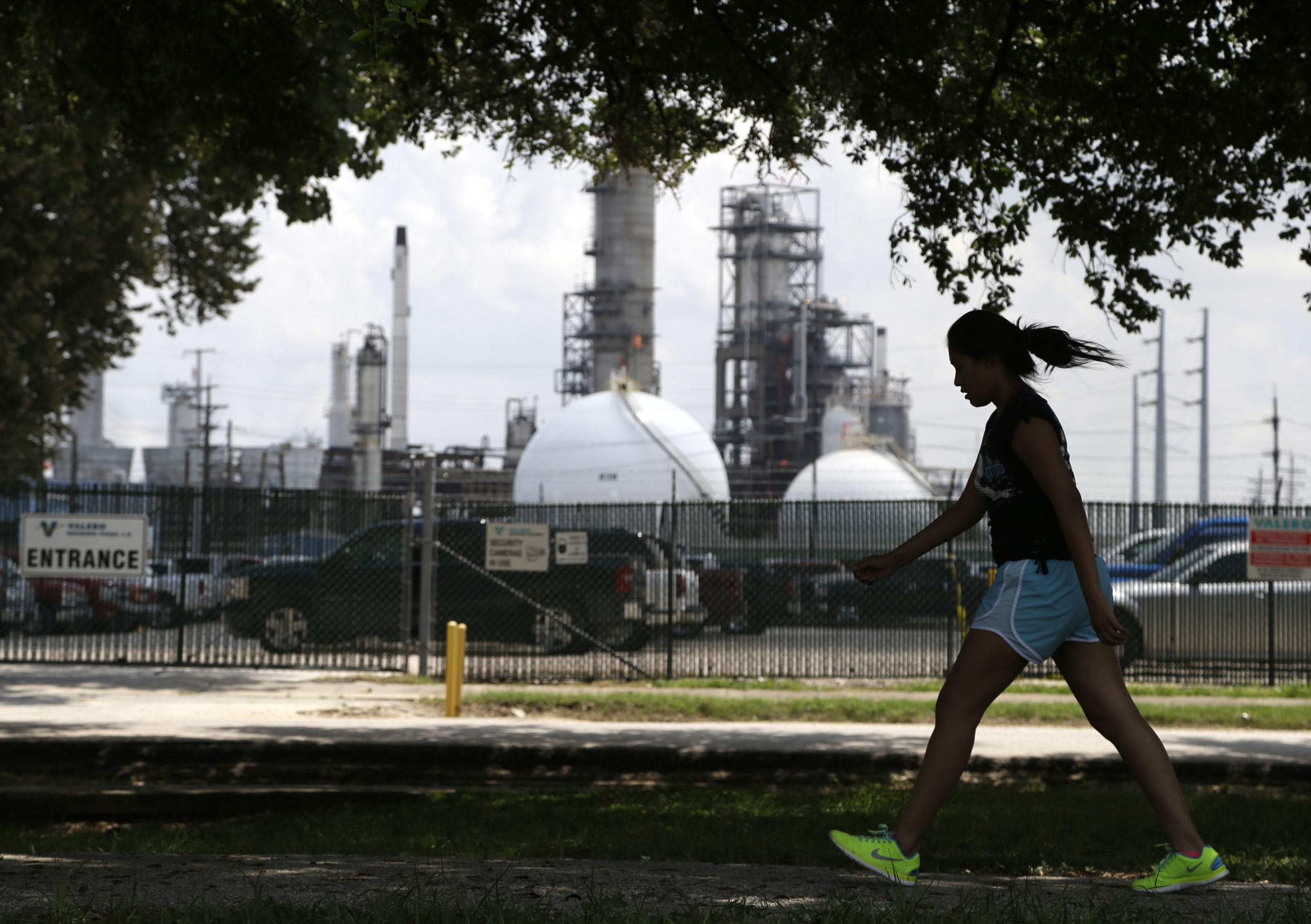 A teenage girl walks around the track of a park across the street from the Valero refinery Monday, Aug. 4, 2014, in the Manchester neighborhood of Houston.