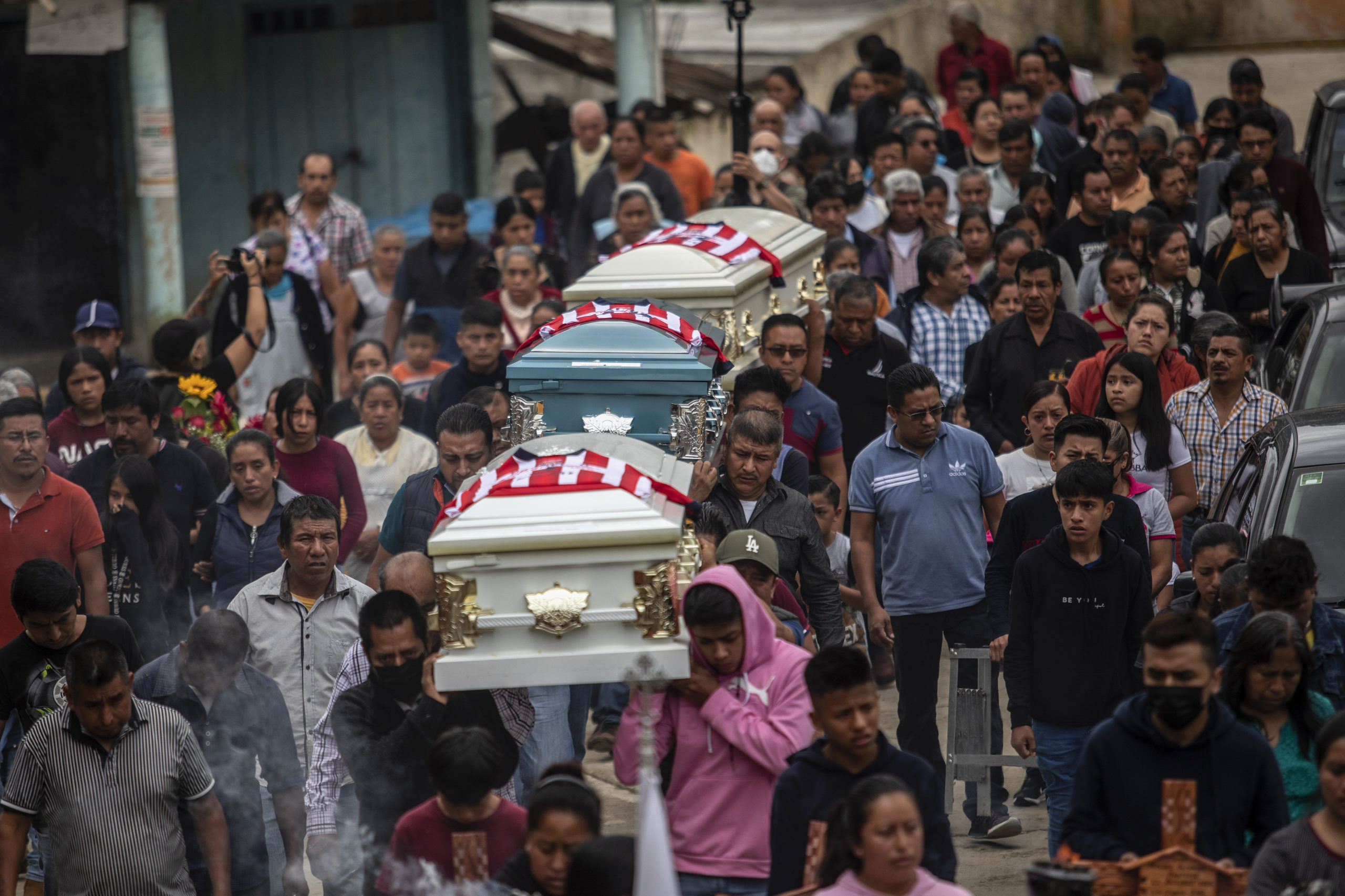 People carry the remains of Jair Valencia, Misael Olivares, and Yovani Valencia for a funeral Mass in San Marcos Atexquilapan, Veracruz state, Mexico. The three teens, all cousins, were those lost among the 53 migrants who died inside a semitrailer in San Antonio.
