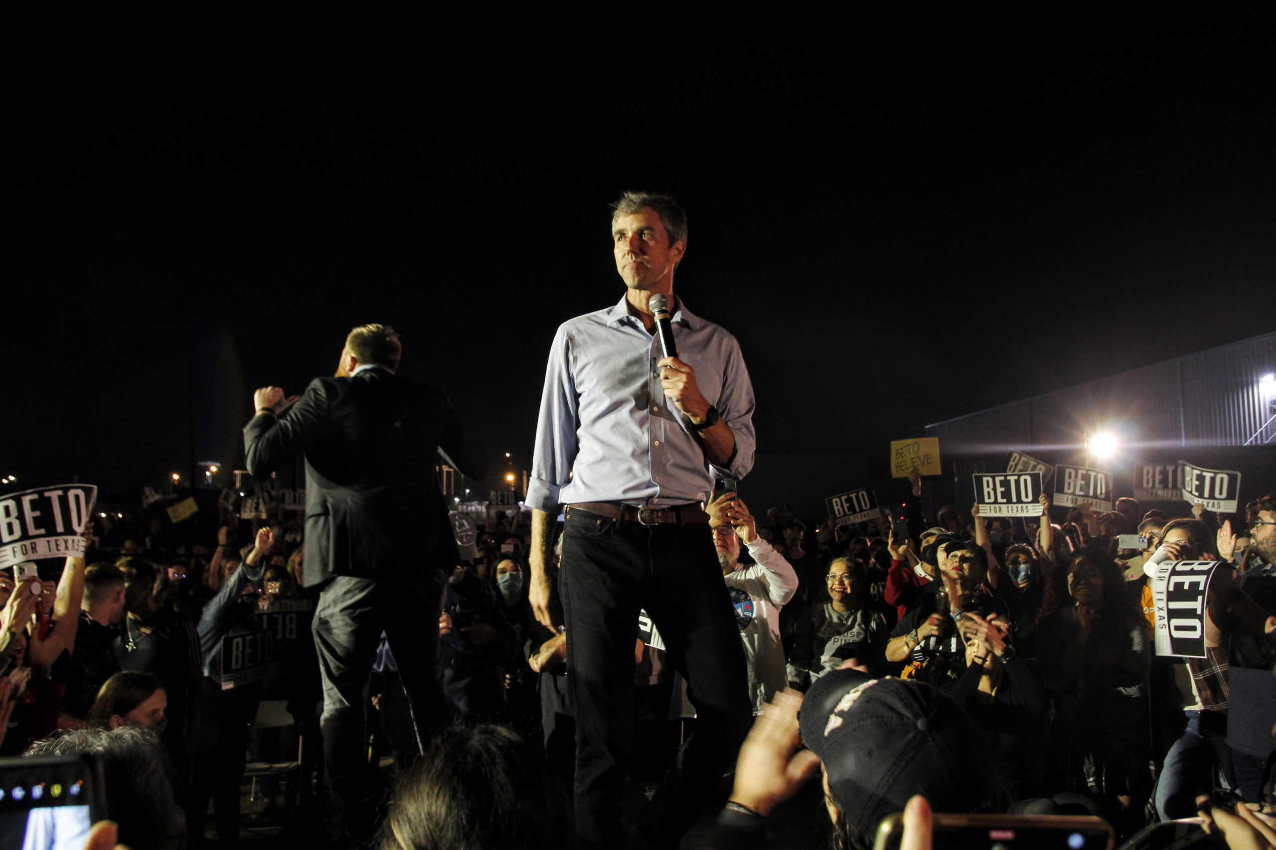 Beto O'Rourke stands confidently among a crowd in Fort Worth at night