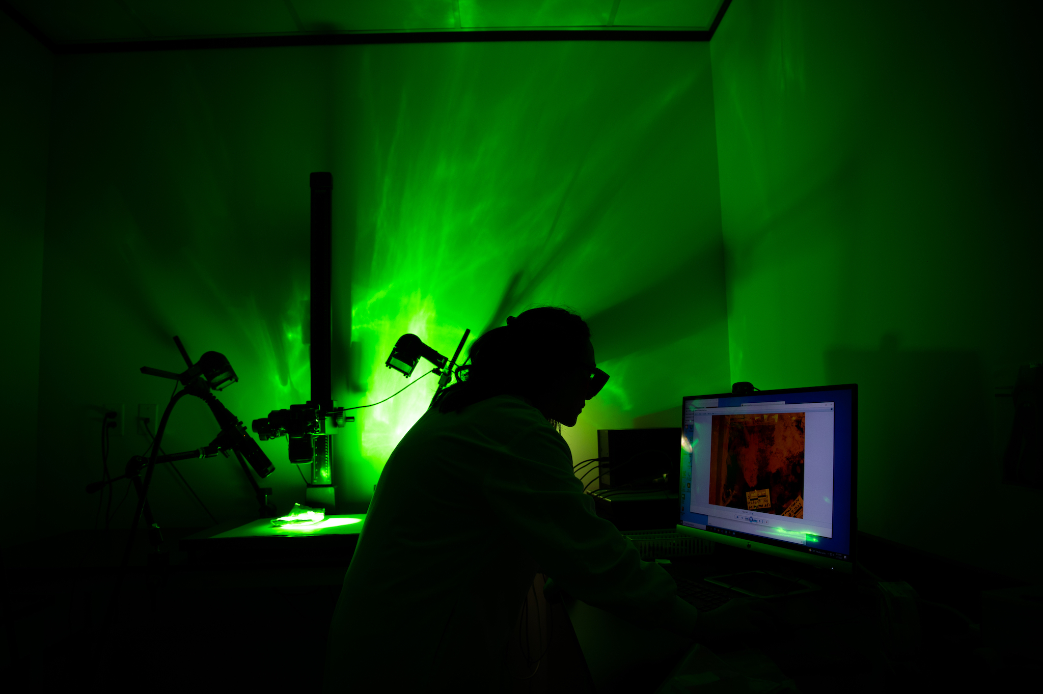 In a darkened room at Houston's crime lab, a forensic scientist is silhoutted against their equipment in the weird green glow it produces.