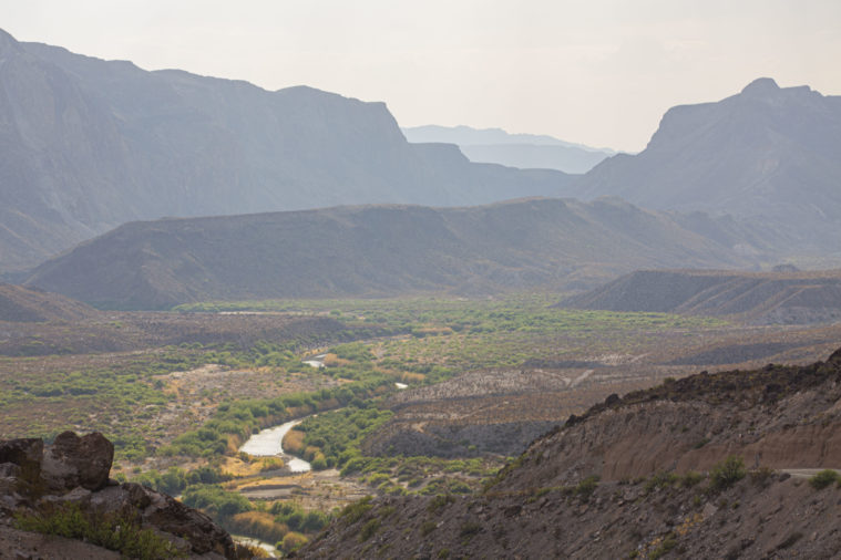 A lush green valley, but the Rio Grande river can be seen snaking through it, visibly low on its river banks. 