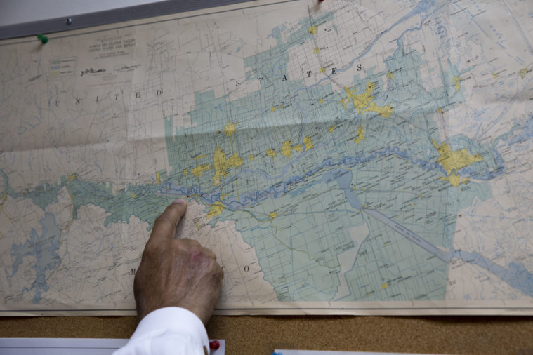 A hand in a dress shirt points at a map of Texas and Mexico.