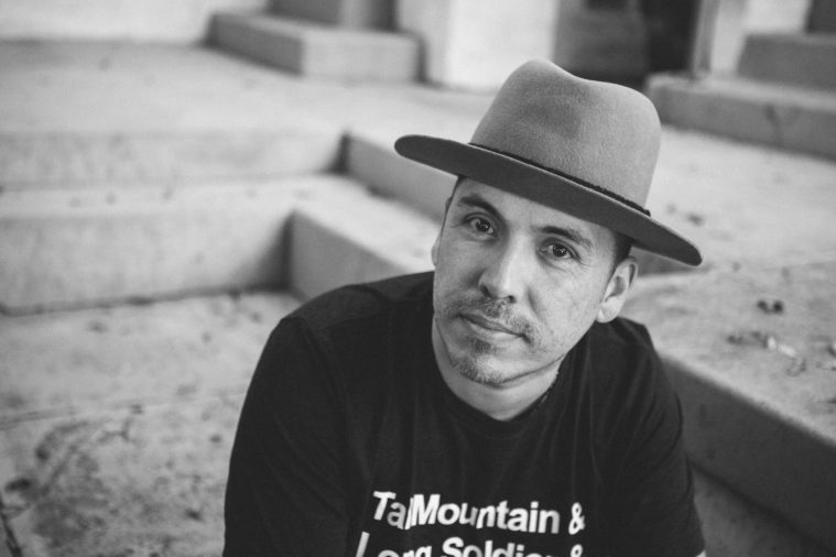 A black and white photo of Joaquin Zihuatanejo, a latinx man wearing a fedora style hat.
