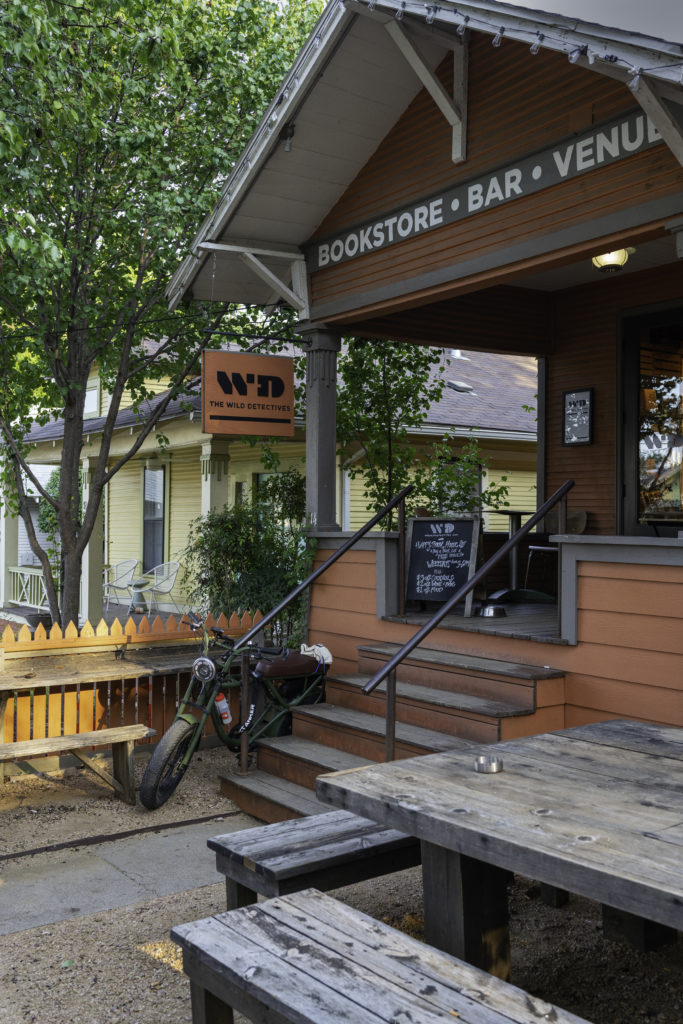 A motorcycle is parked near the welcoming picnic tables in the backyard of the Wild Detectives bookstore and bar in Dallas, Texas.