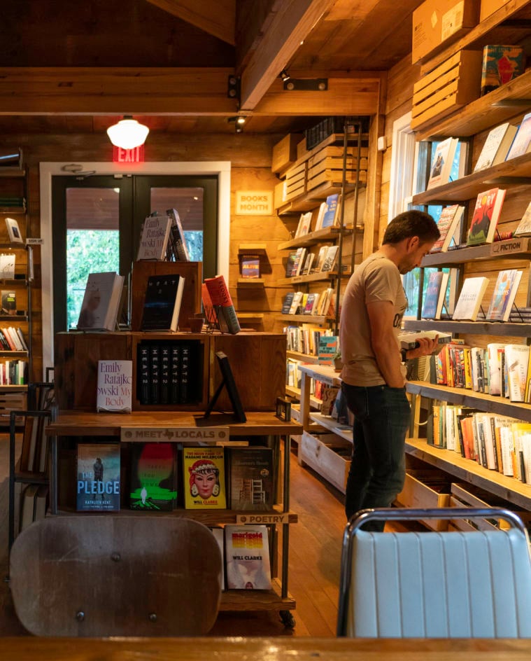 The densely packed bookshelves, displays and wood floors and walls, along with exposed wooden rafters, create a homey and welcoming atmosphere at The Wild Detectives bookstore in Dallas, Texas.