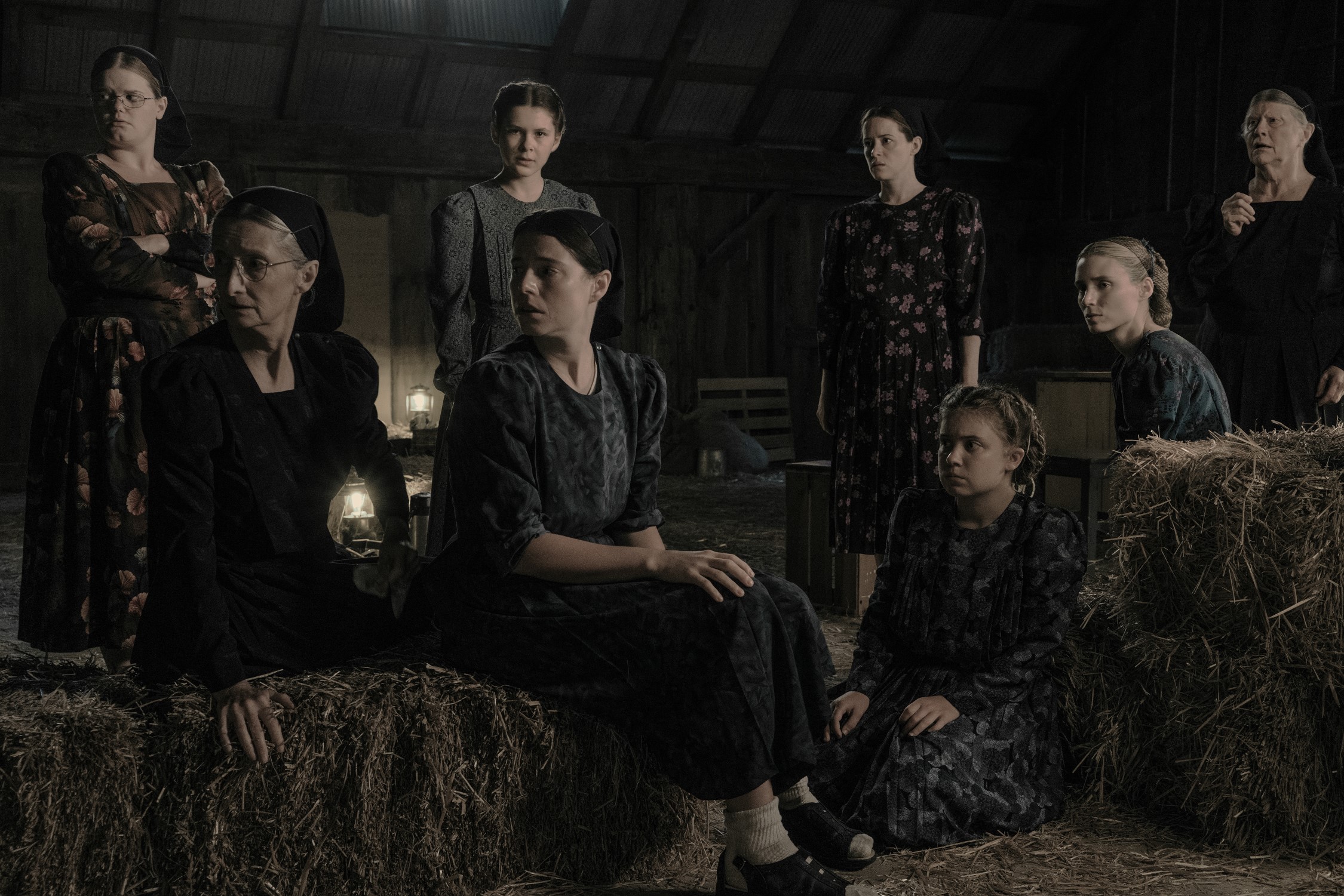 The cast of Women Talking, a group of white women of varying ages, dressed as Mennonites, gather in a barn.