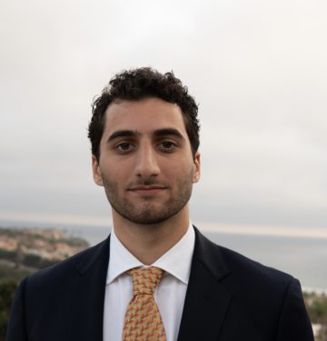 Arman Badrei is dressed in a suit and tie, with a valley and open sky behind him.