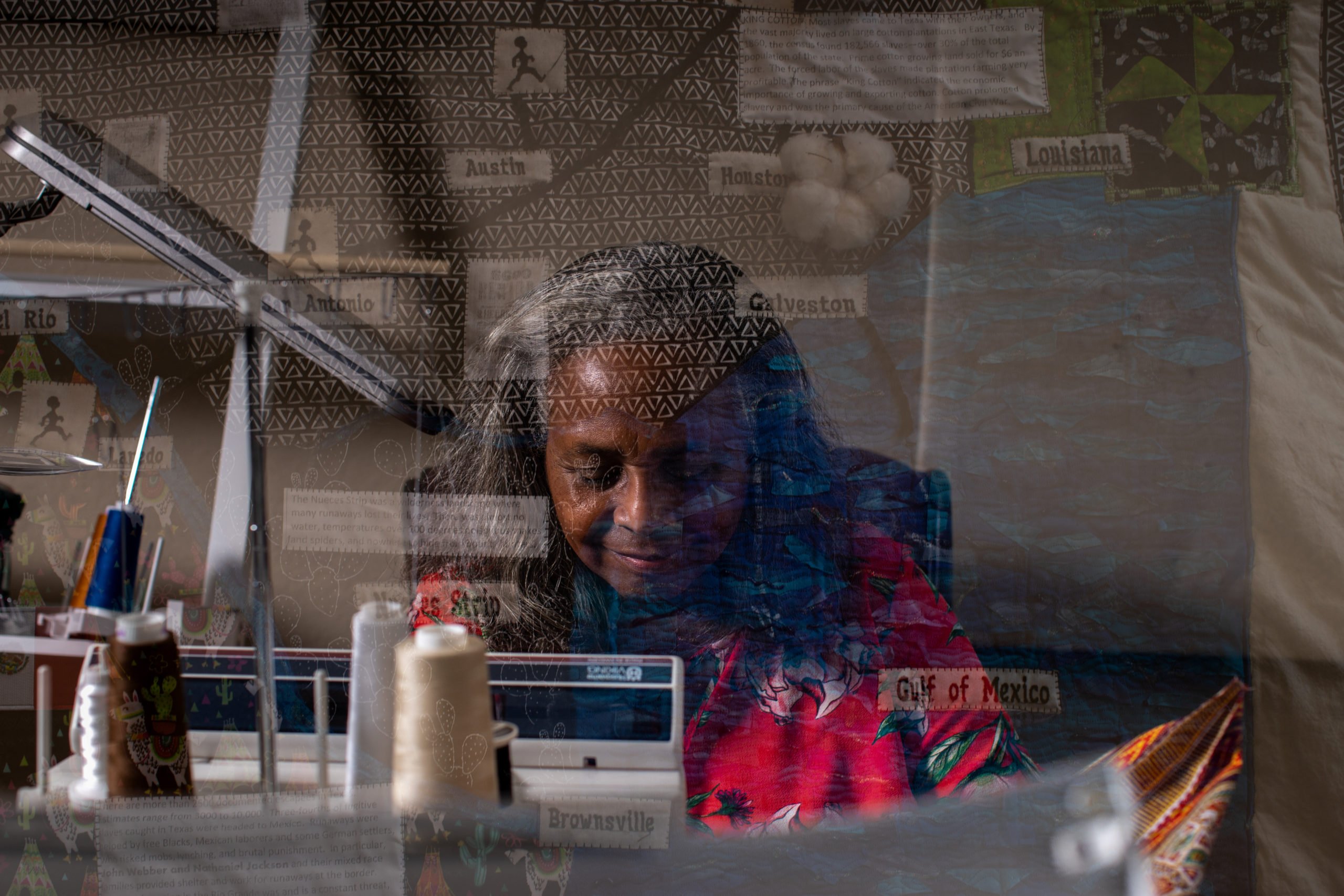 A double exposure shows Lillian Jones, 70, stitching together an item for a friend at her home workshop in Converse overlaid with her quilt, “The Tex Mex Underground Railroad,” on display at the Carver Center in San Antonio on Nov. 17