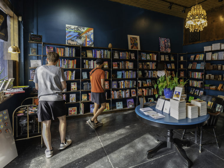 Customers browse the shelves at Poets' Bookshop in Dallas, walking past floor to ceiling bookshelves and a display of Texas books. 