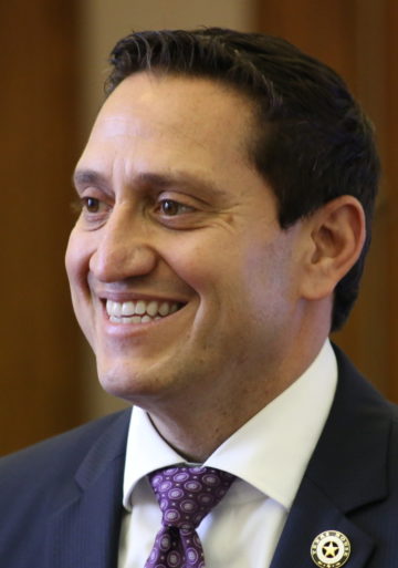 A close-up portrait of Trey Martinez Fischer smiling, wearing a suit and tie.