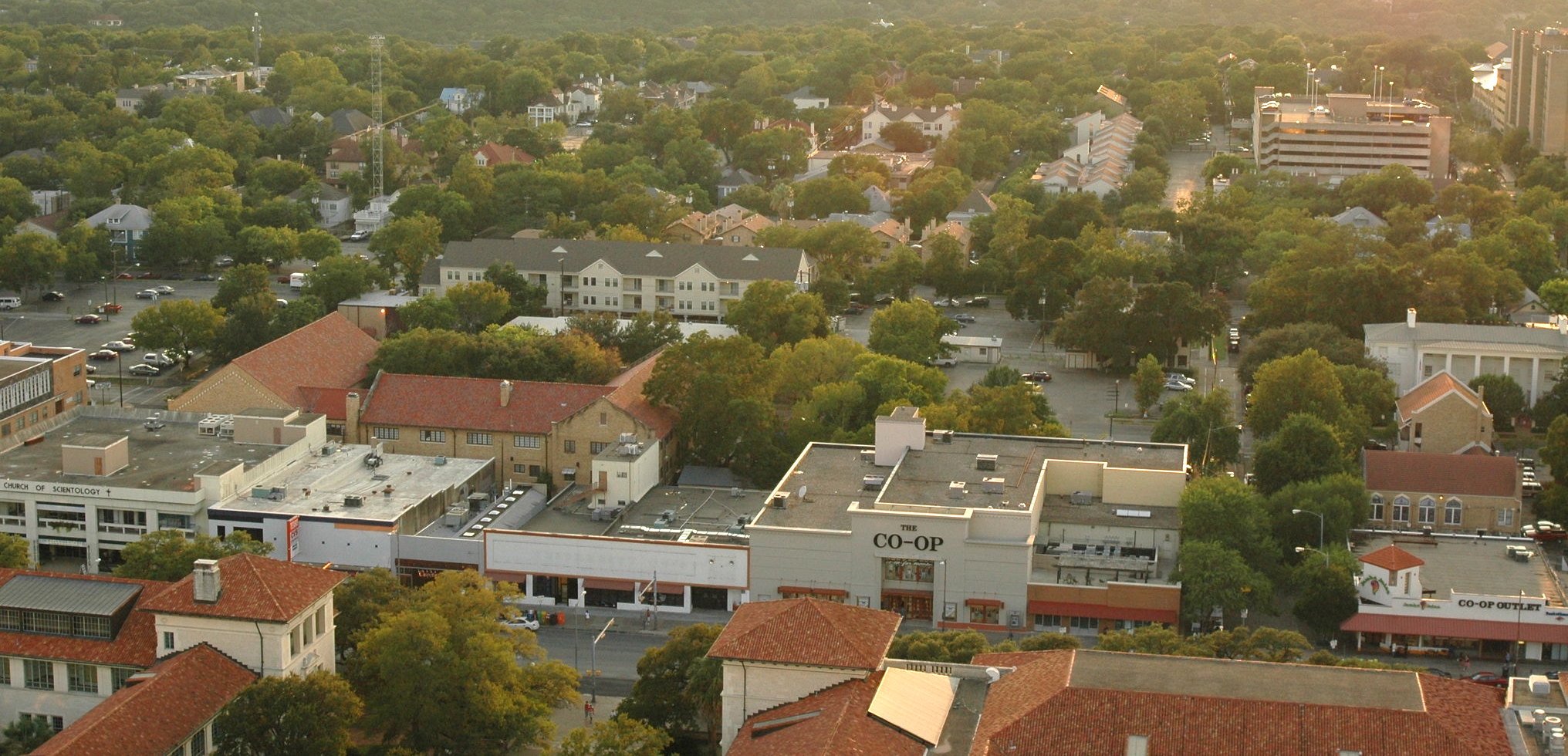 An aerial shot looking West from the UT-Austin campus, looking at the West Campus neighborhood as it once appeared, a tree-lined neighborhood with small cute houses.