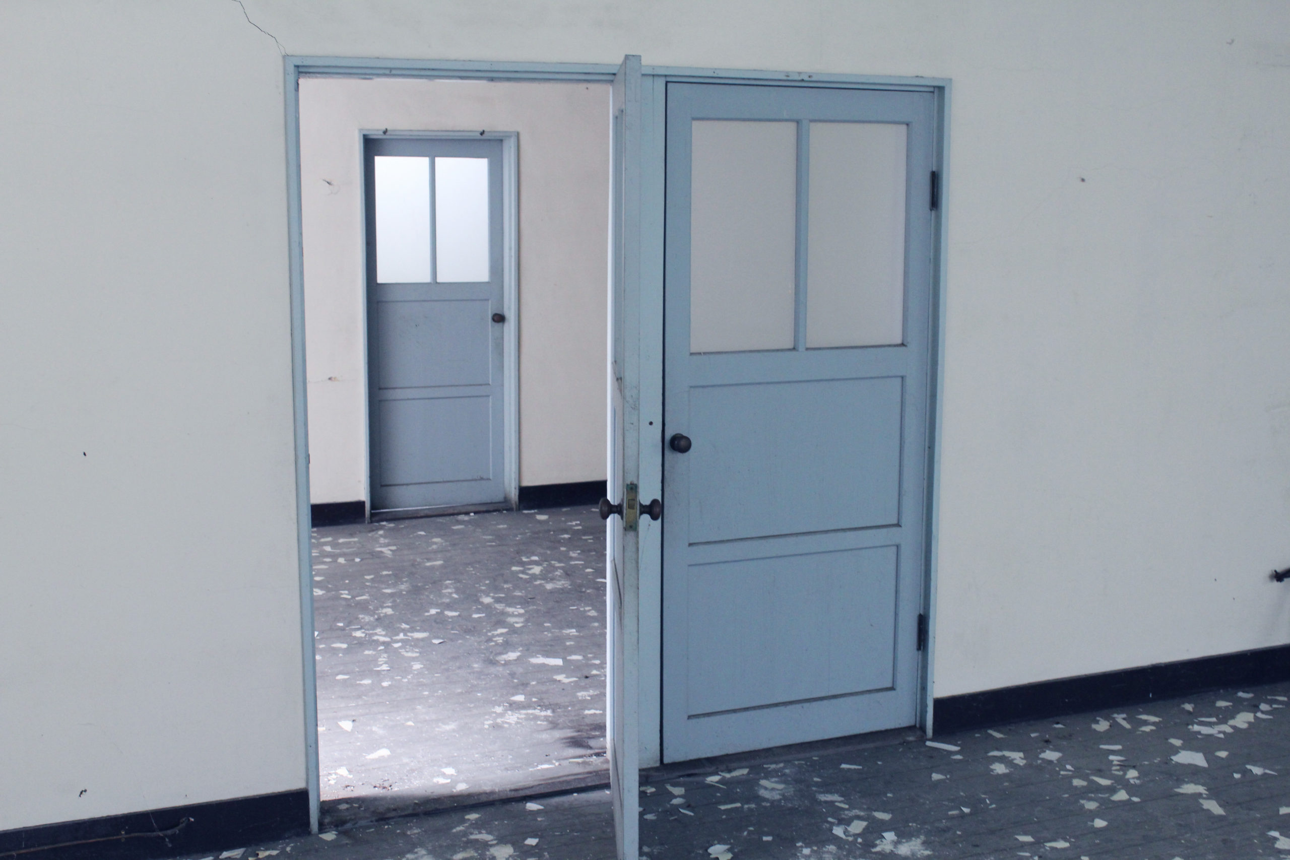 A classroom door with lock. The door is blue and wide open.
