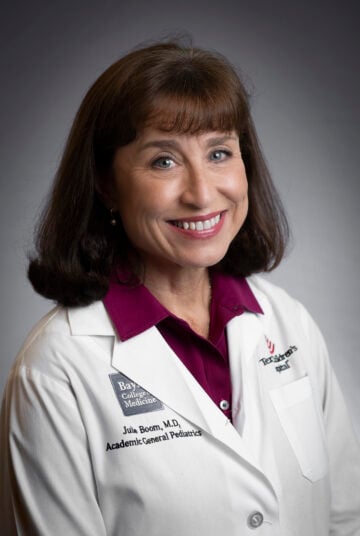 Julie Boom is a smiling woman with shoulder length brown hair, in a medical jacket from Texas Children's Hospital.
