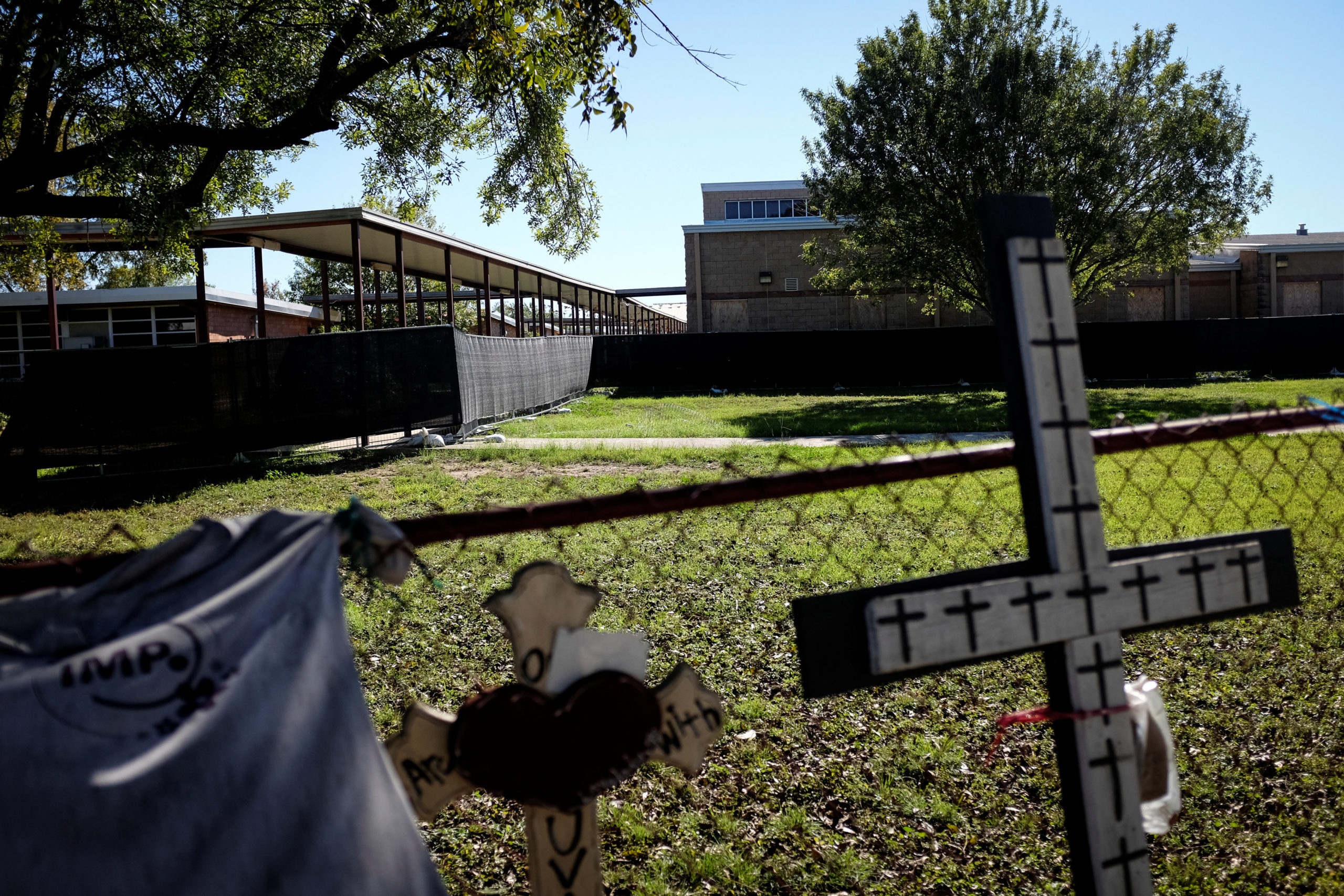 A glimpse of the memorial in front of Robb Elementary. Some handmade crosses can be seen up against the school yard fence.