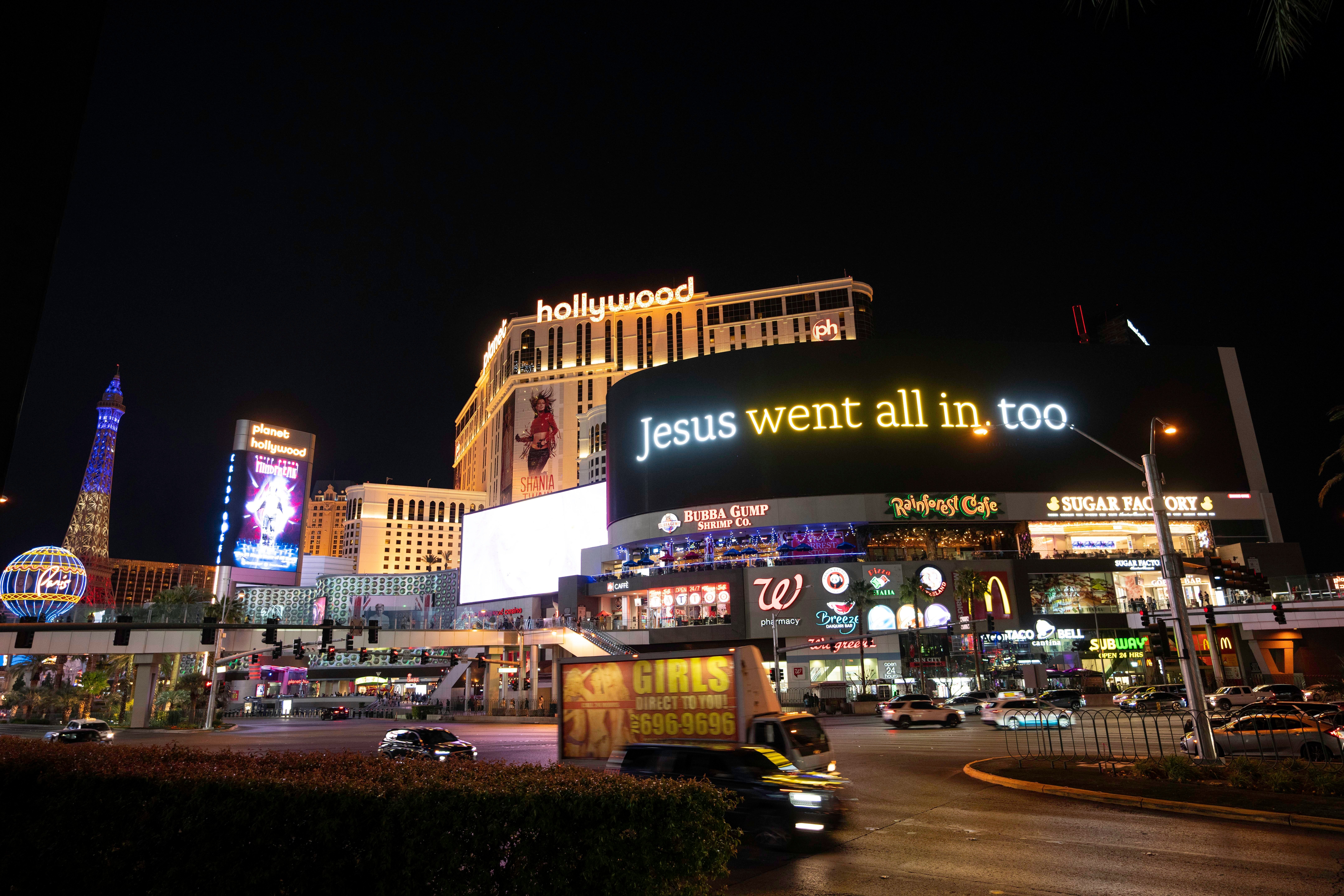 A lit billboard for the He Gets Us campaign seen in Las Vegas on the strip at night. It reads "Jesus went all in, too."