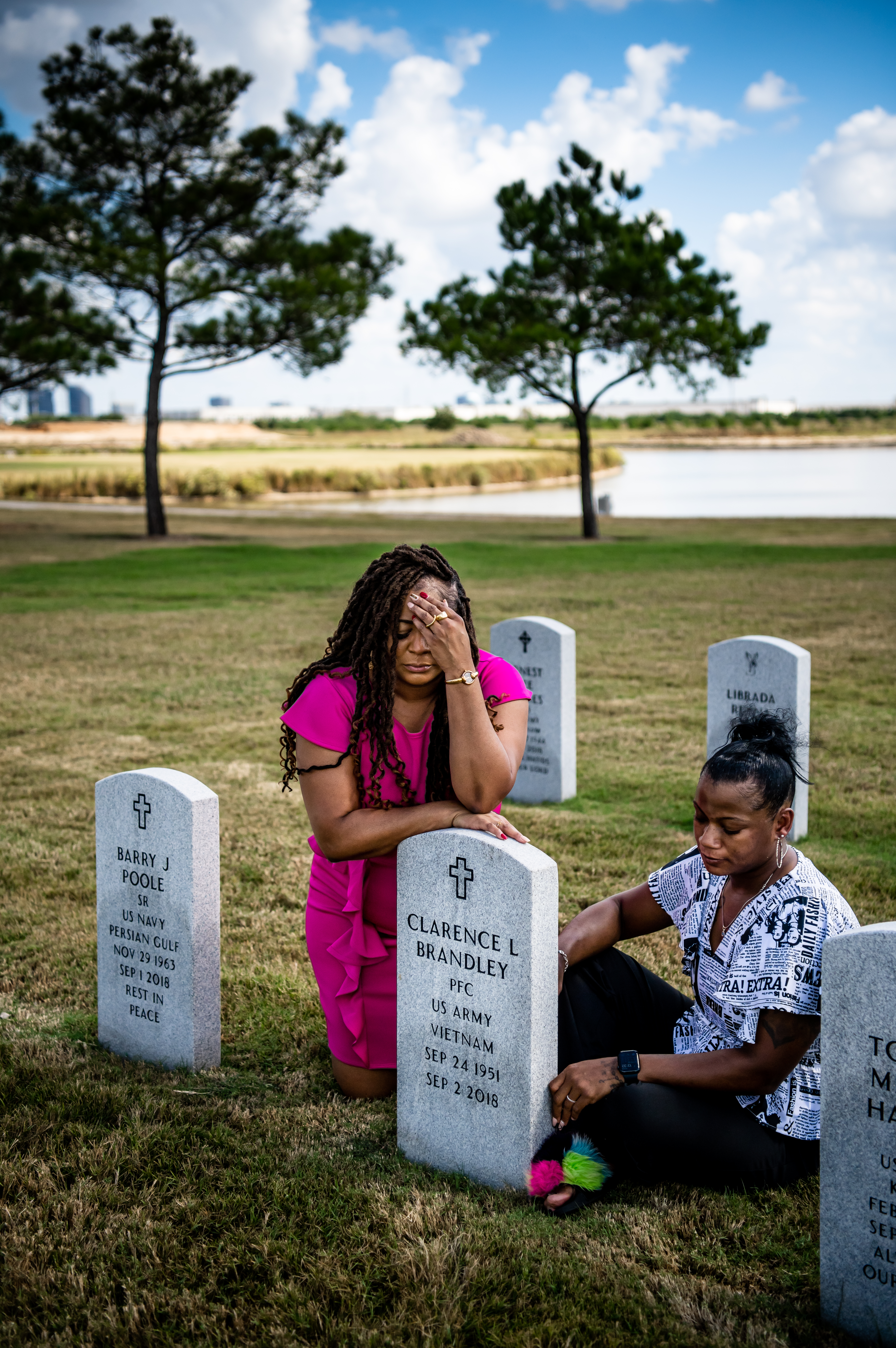 Two Black women gather mournfully around the grave of Clarence Brandley, which is in a well-maintained graveyard by a small lake.