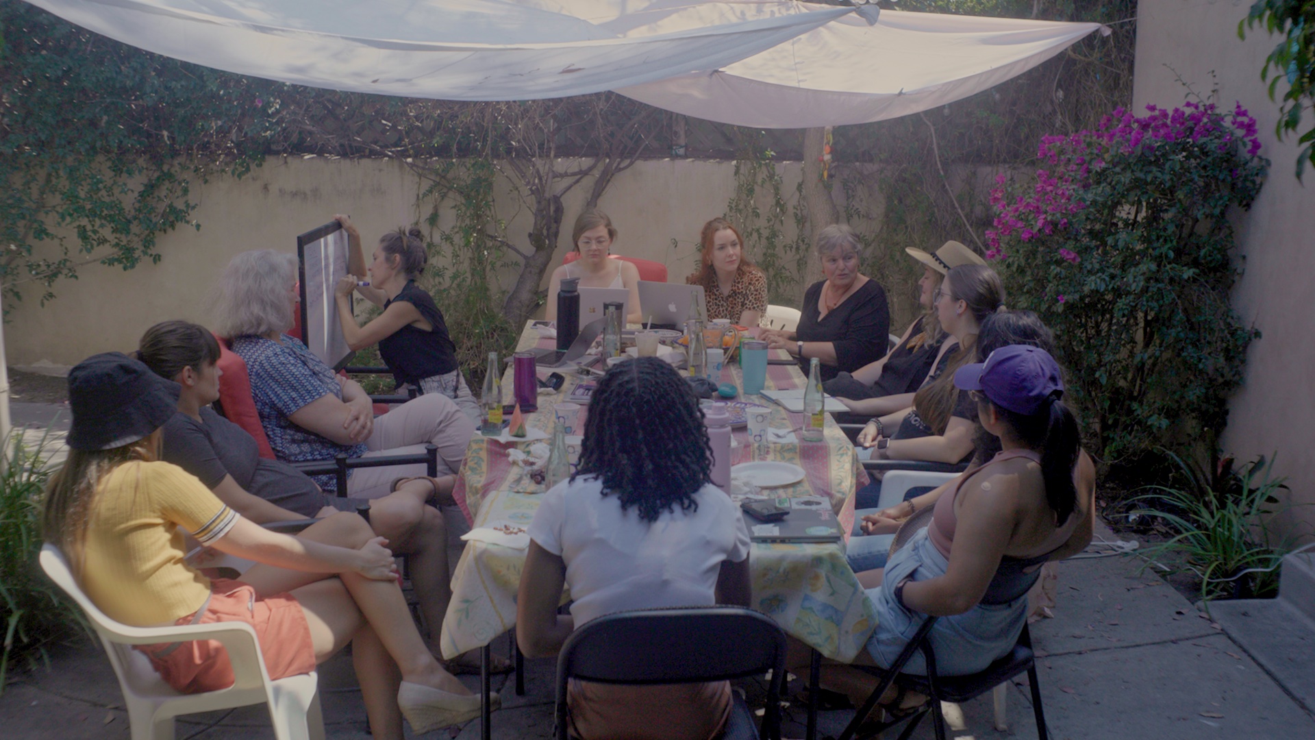 The women who organize the Plan C abortion pill information werbsite having an outdoor meeting on a patio picnic table. One is writing on a whiteboard.