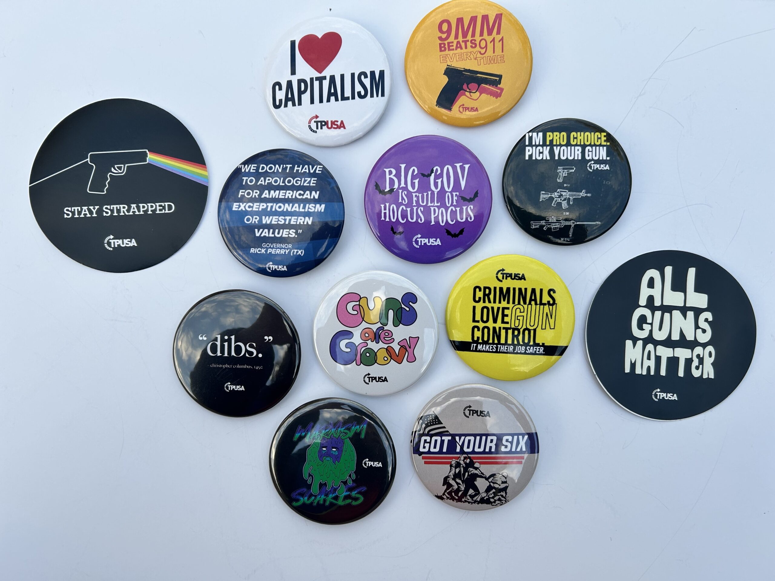 A collection of buttons from TPUSA with mottos like "I Heart Capitalism", "Guns are groovy", "All Guns Matter" and other designs meant to appeal to young people.