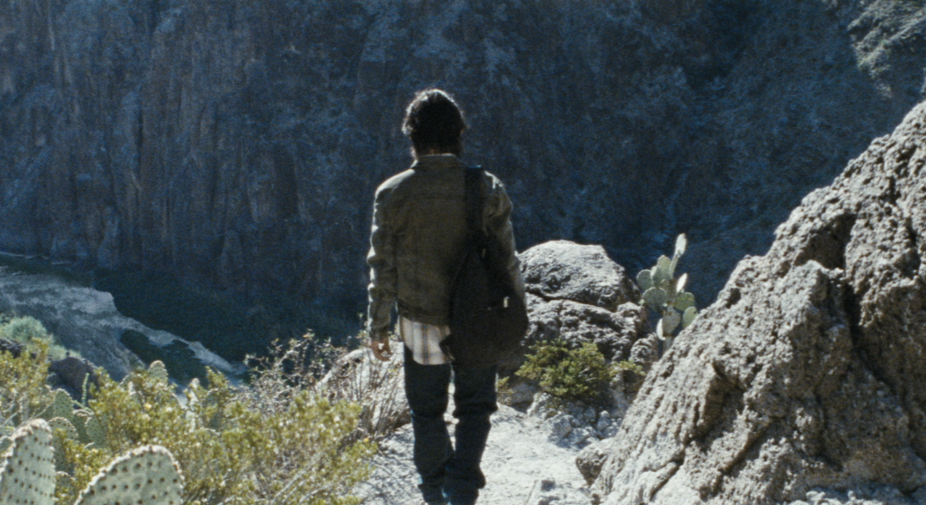 From Deadland: A man walks away from the screen, beside cactus, high above the Rio Grande.