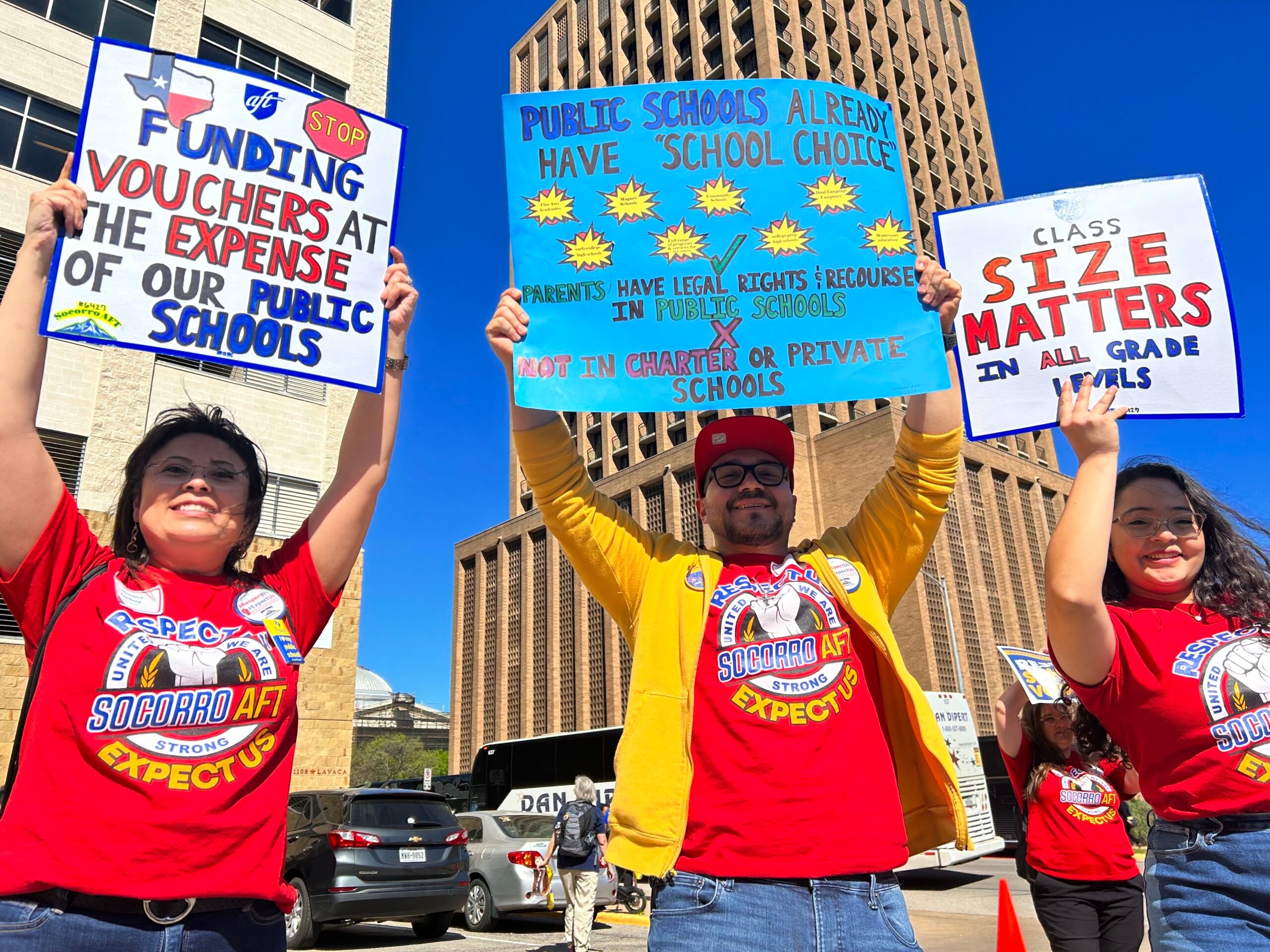 Three people gather outside government buildings in Austin with signs reading: "Stop funding vouchers at the expense of our public schools" "public schools already have school choice: parents have legal rights and recourse in public schools cnot in charter or private schools" and "Class size matters in all grade levels". Property tax cuts and voucher programs threaten to overwhelm an already struggling school system.