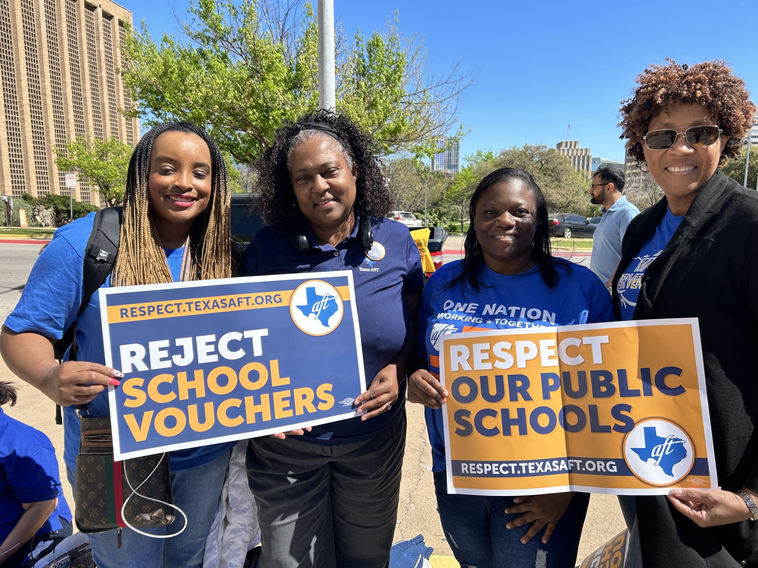 Four Black women gather outside in Austin with signs reading "Reject School Vouchers" and "Respect our public schools". Vouchers, along with property tax cuts, threaten public schools already overwhelmed by teacher attrition.