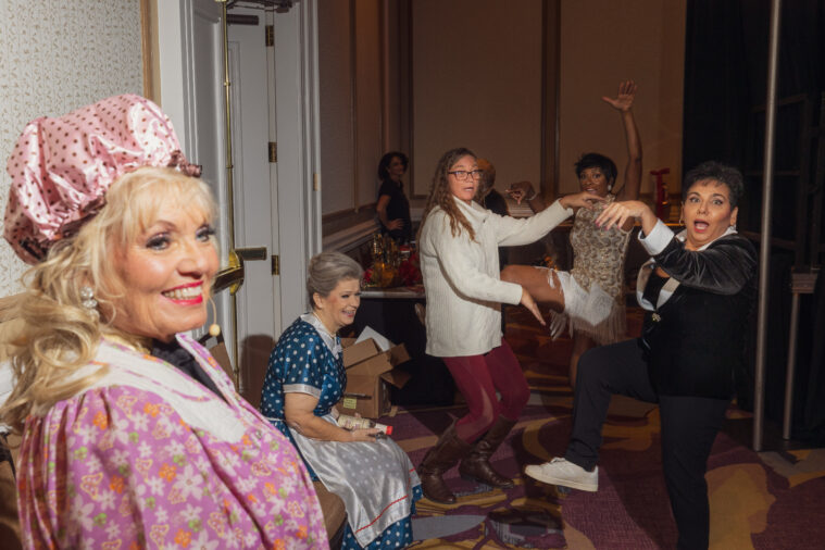 About a half dozen women laugh or pose in silly positions as they gather in a backstage area at Ms. Texas Senior America.