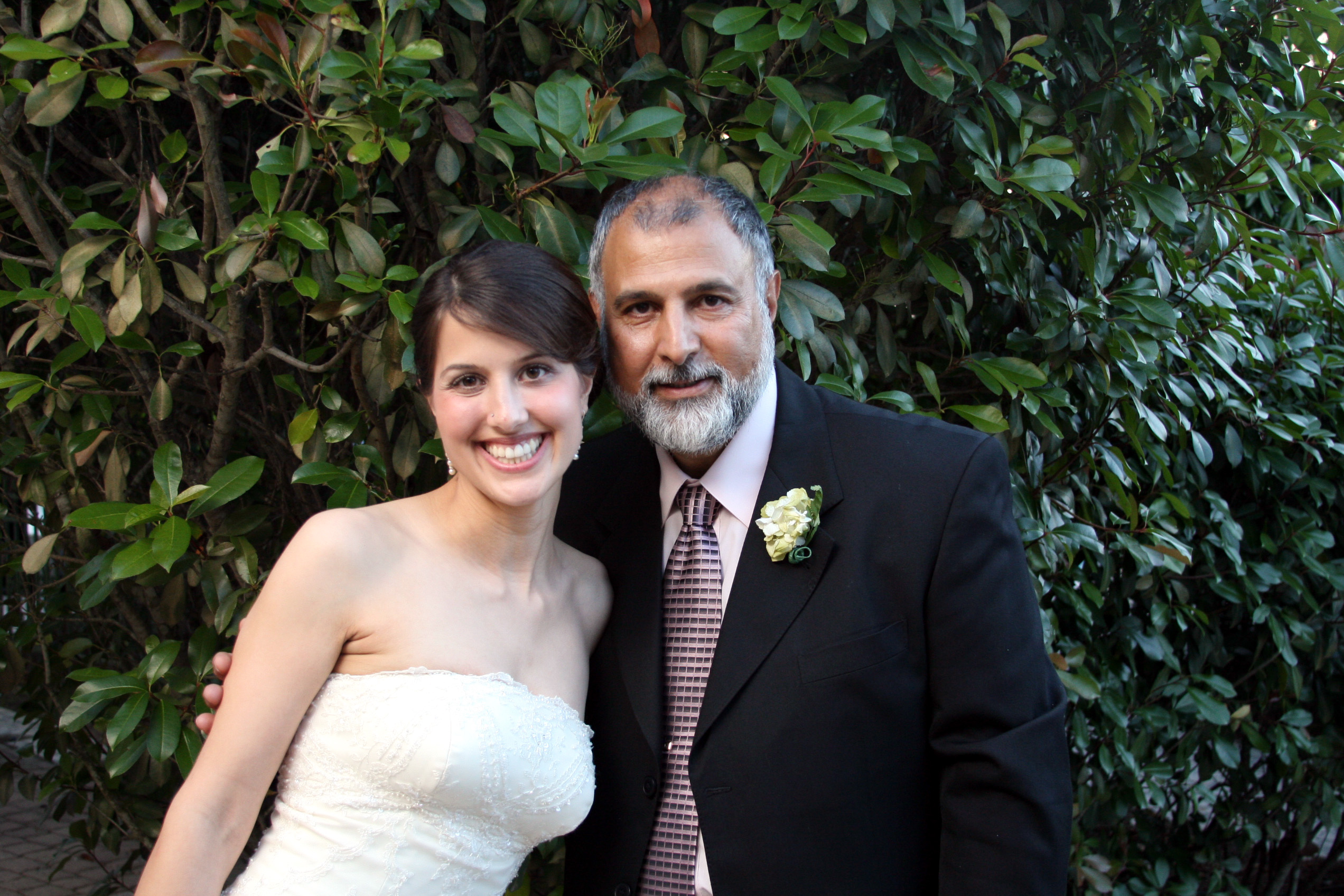 The author poses with her father, an older Iranian man, in a tuxedo. She's in a wedding dress.