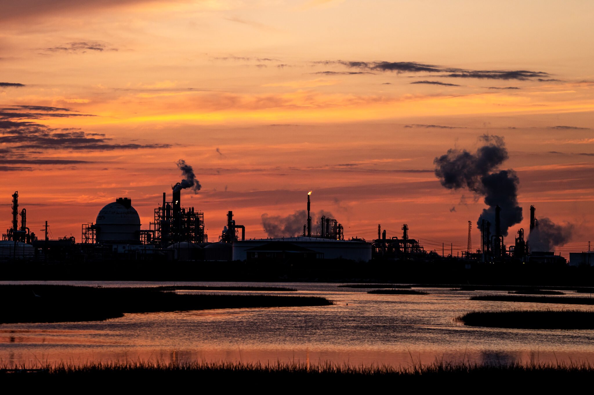 At sunrise or sunset, a Dow petrochemical plant can be seen along the Brazos River, its smokestacks steaming.