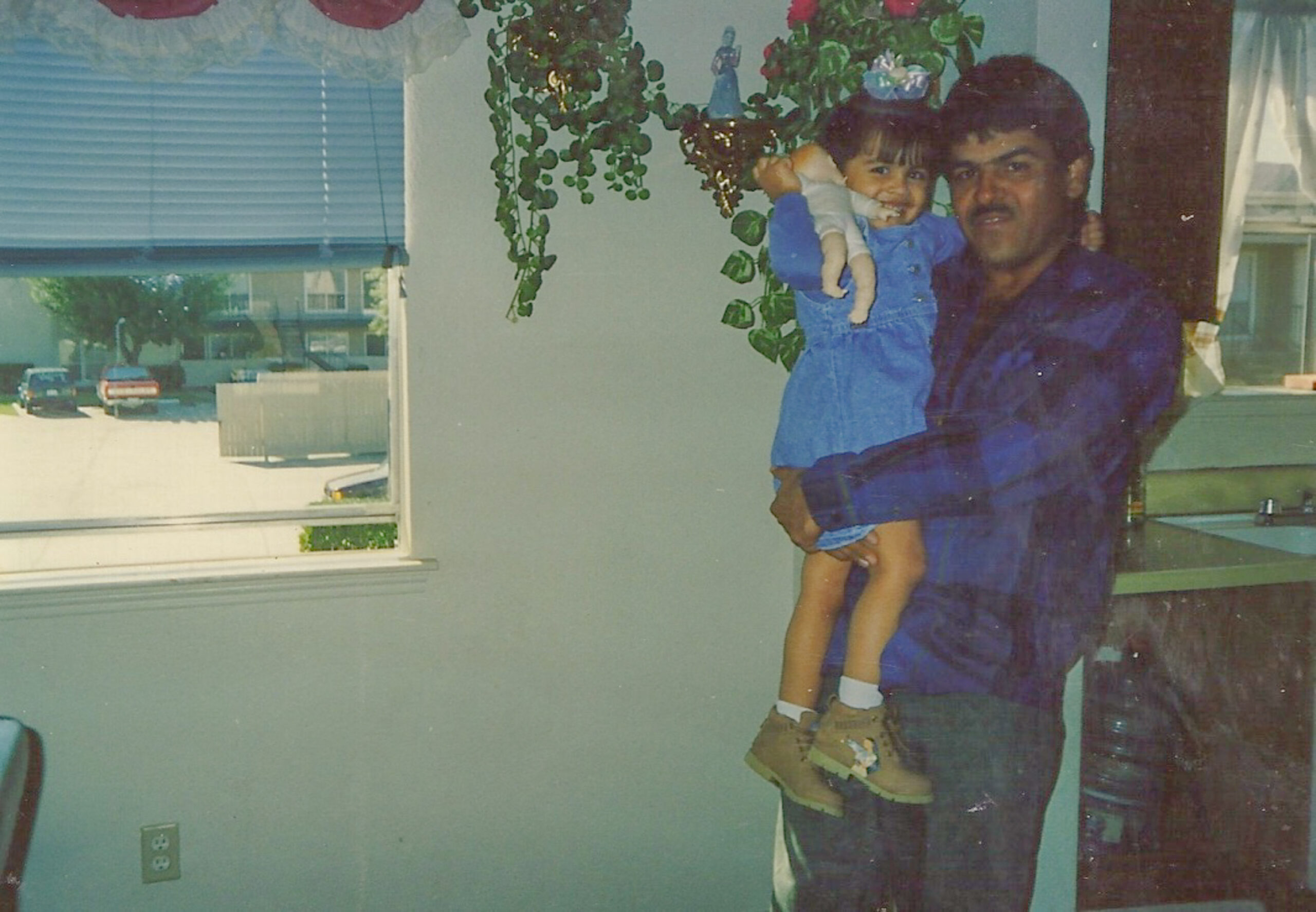 Antelmo Ramirez, as a younger man, holds his young daughter inside a dwelling.