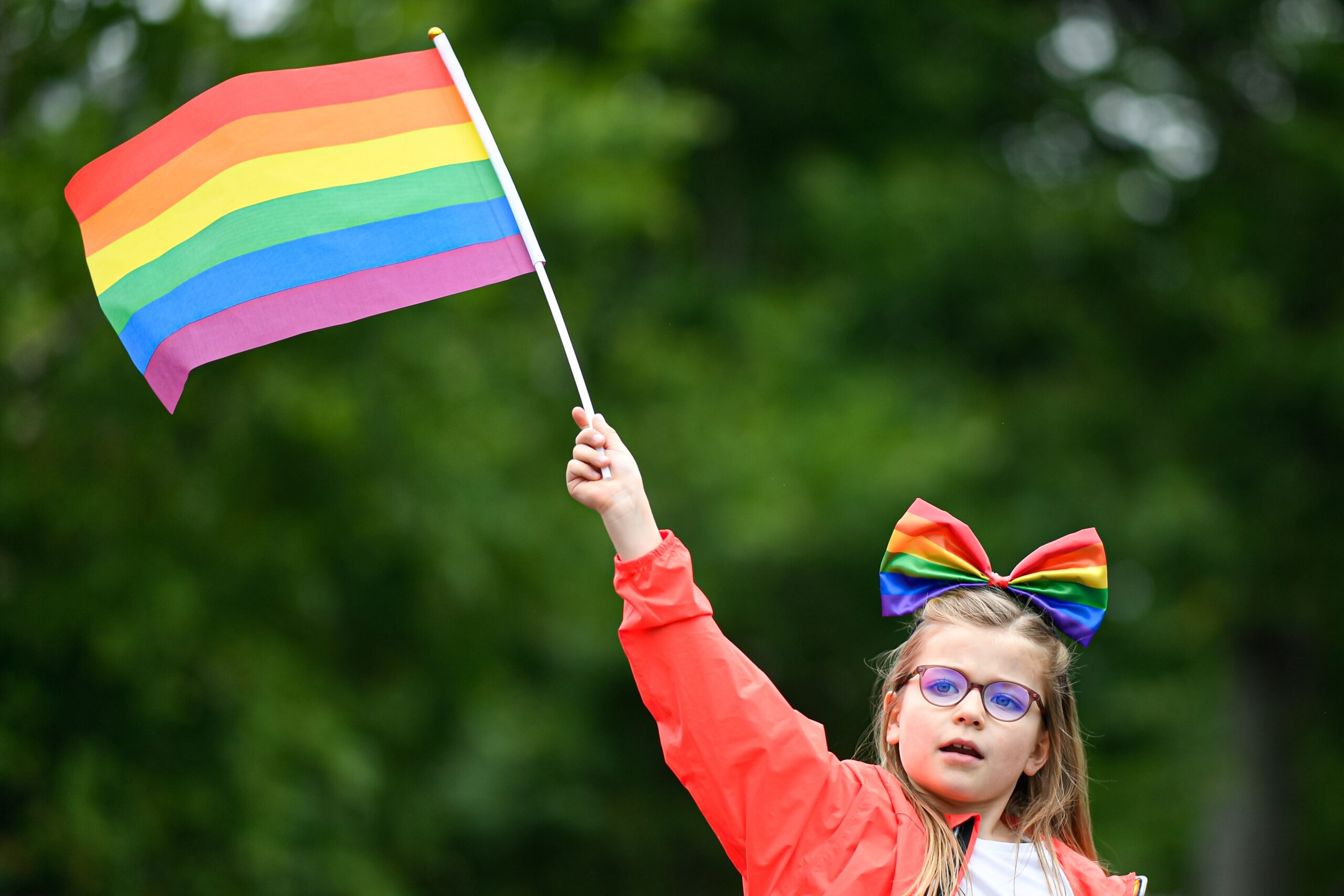 A little girl (child) waving a rainbow flag in the Pride March (Gay Pride Month, "Marche des Fiertes") for the inclusion and rights of the LGBTQI+ in Paris, France on June, 25, 2022.