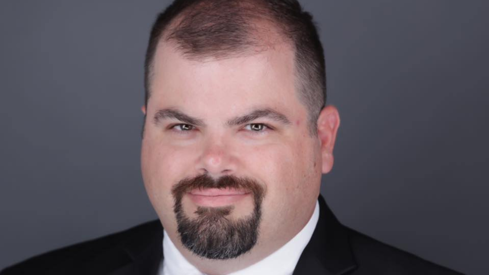 Dave Shafer, a white man in a suit and tie with a neatly trimmed moustache and beard.