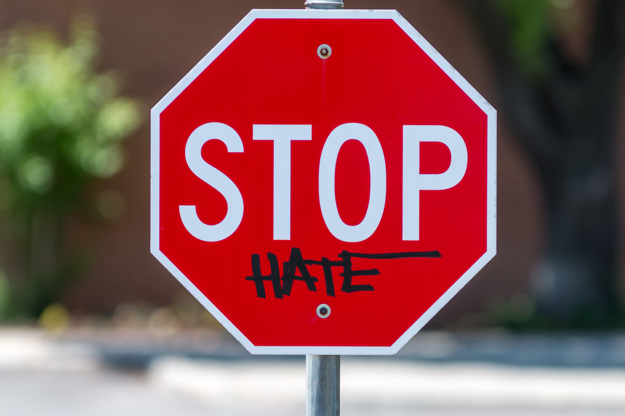 Stop sign with graffiti reading "STOP hate"