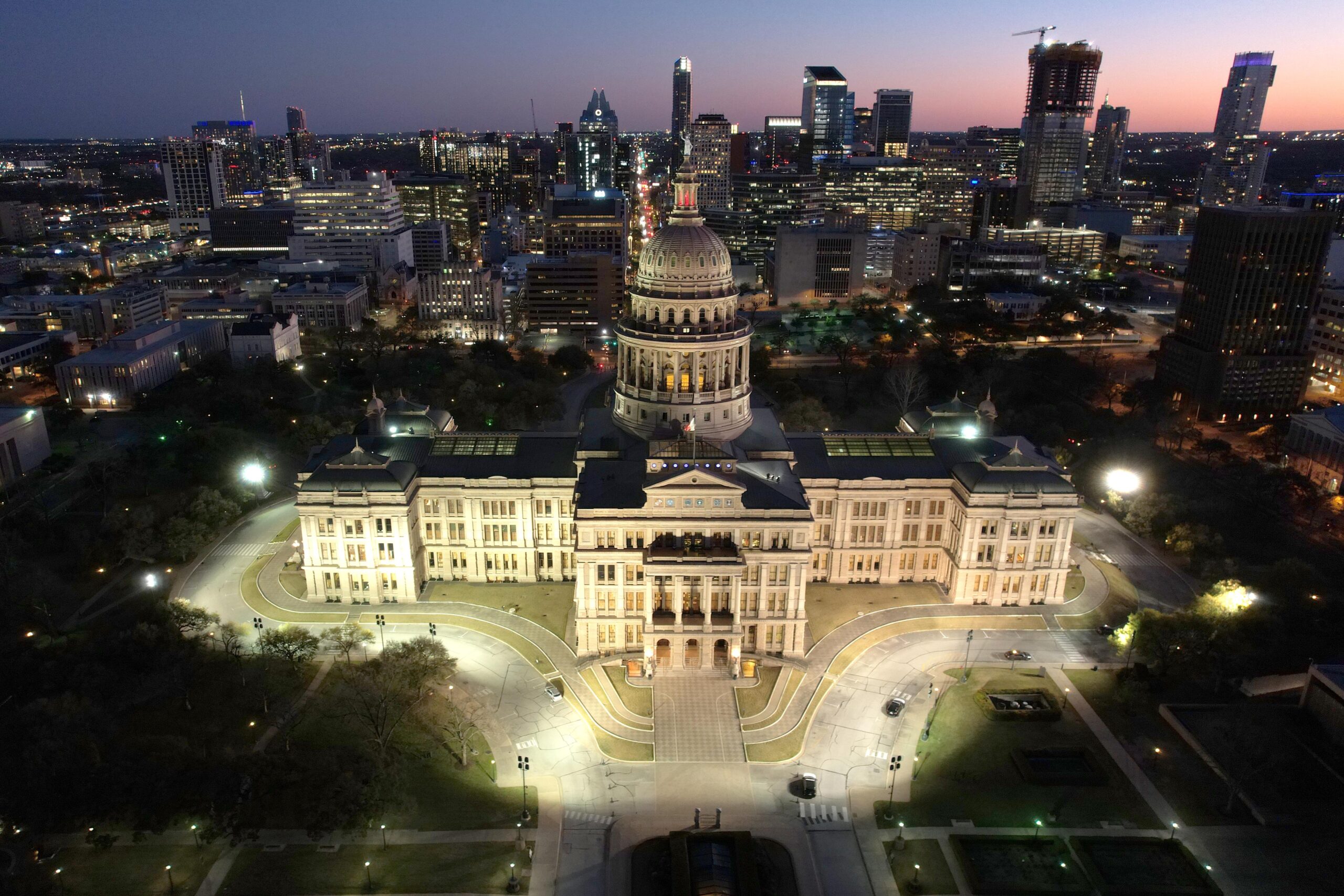 The Texas Capitol building seen from overhead, lit up at night.