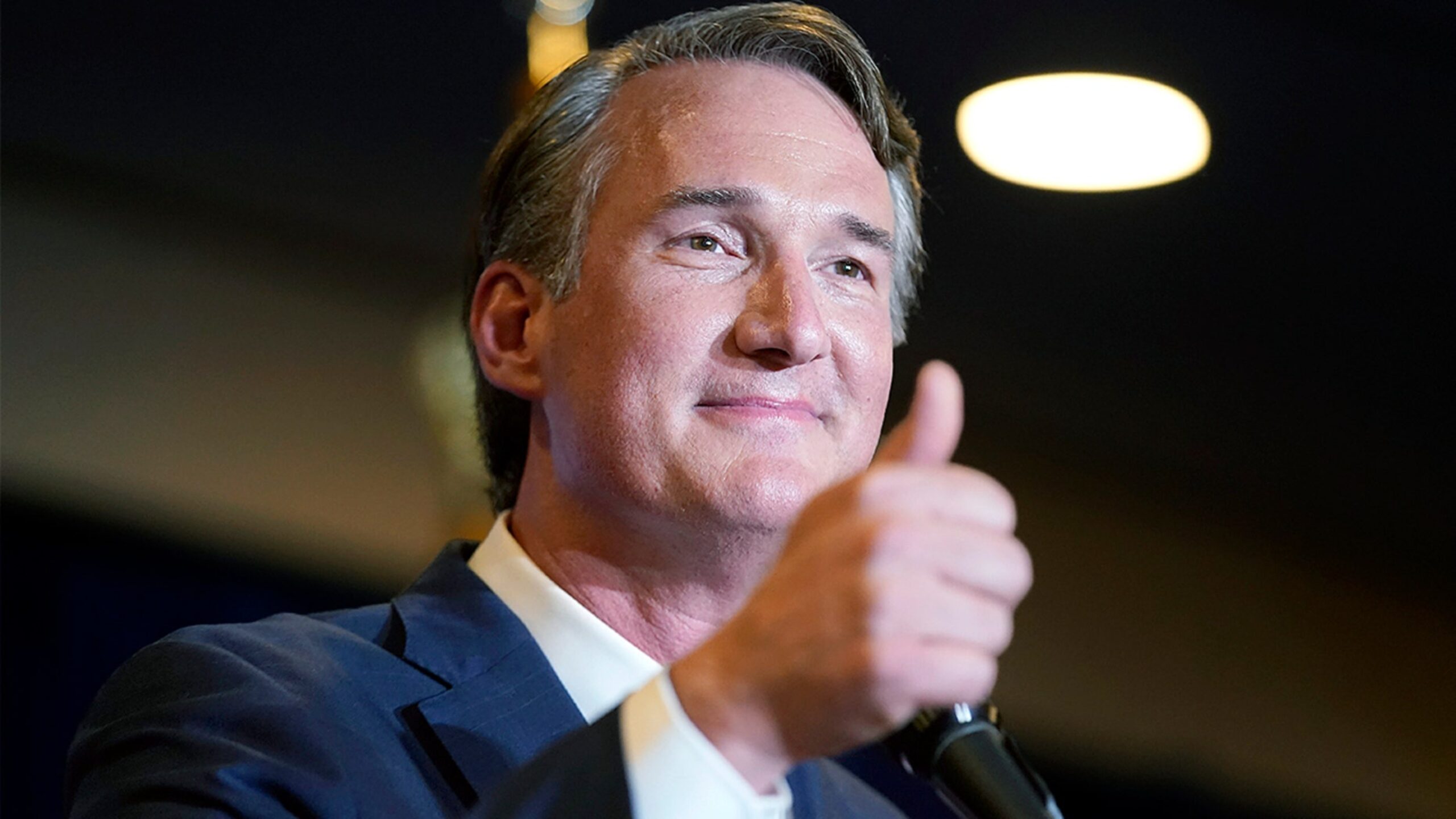 Glenn Youngkin, a white man with short gray hair in a suit, gives a thumbs up.