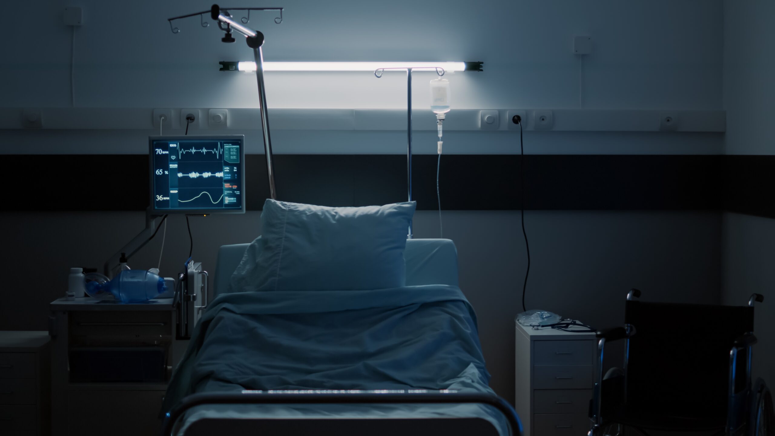An empty hospital bed in a dimly lit room.