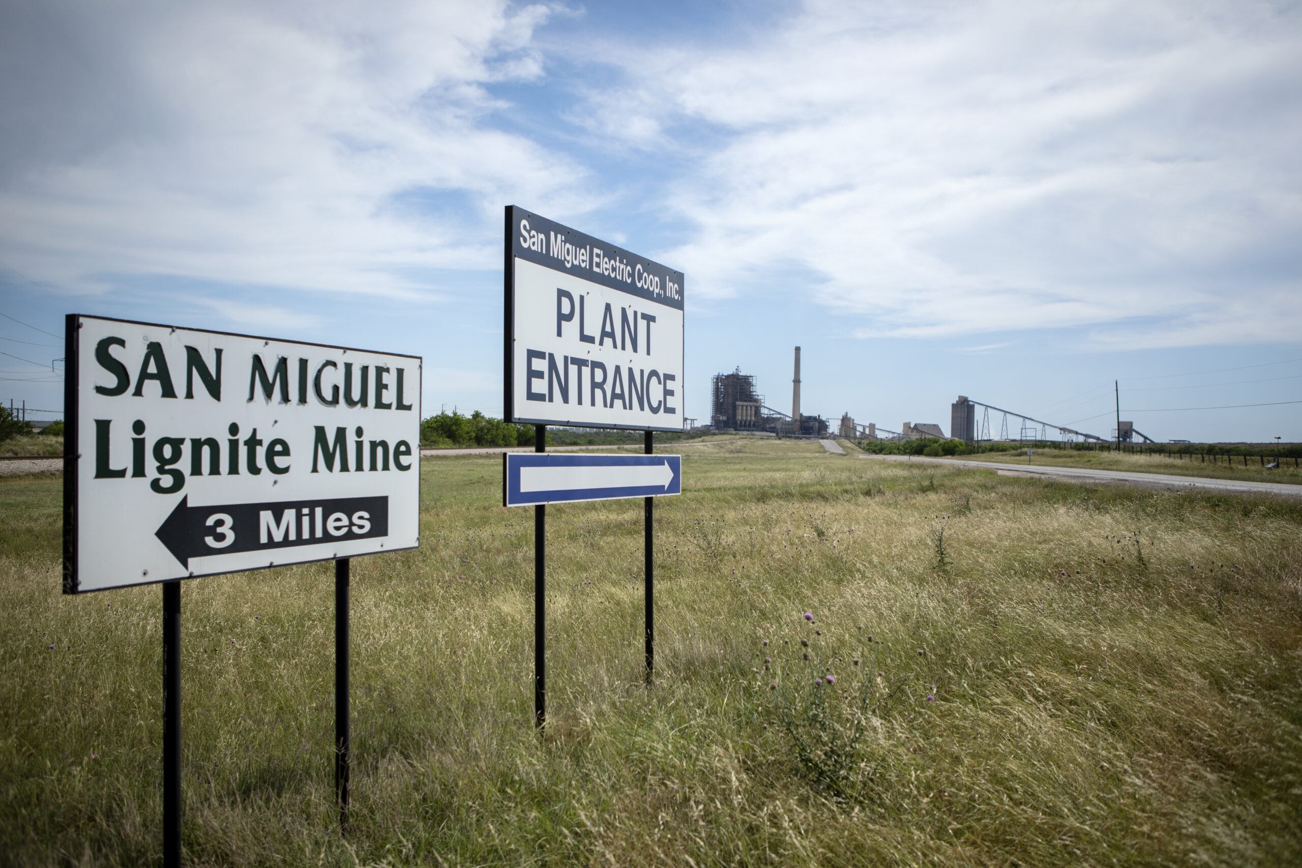 Signs point to the entrance of the San Miguel Electric Cooperative power plant and the San Miguel Lignite Mine on April 29, 2019.