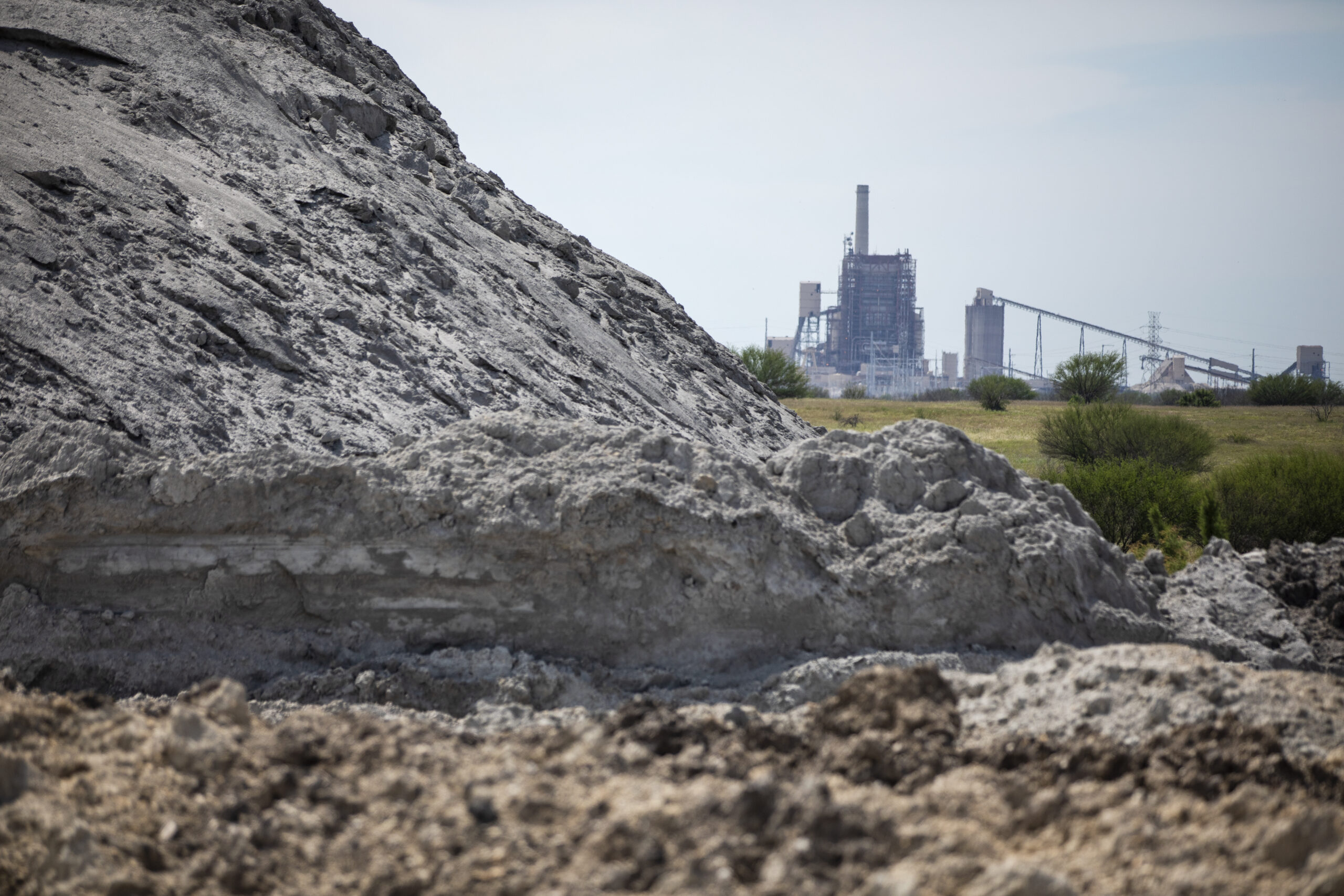 A view of the San Miguel Electric Cooperative power plant with coal ash in the foreground.