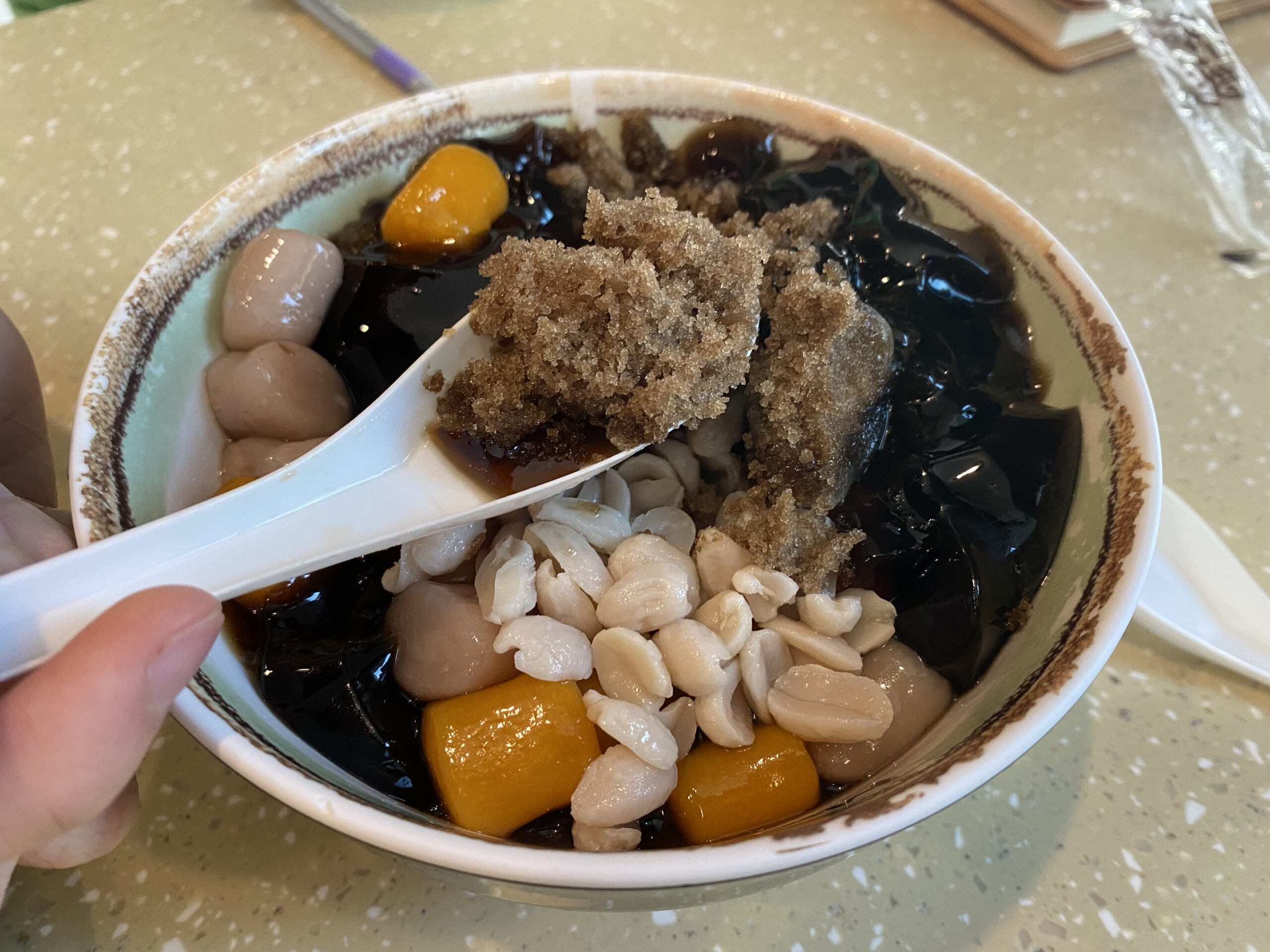 A spoon scoop up the colorful, gelatinous textured icy grass jelly treat from Meet Fresh.