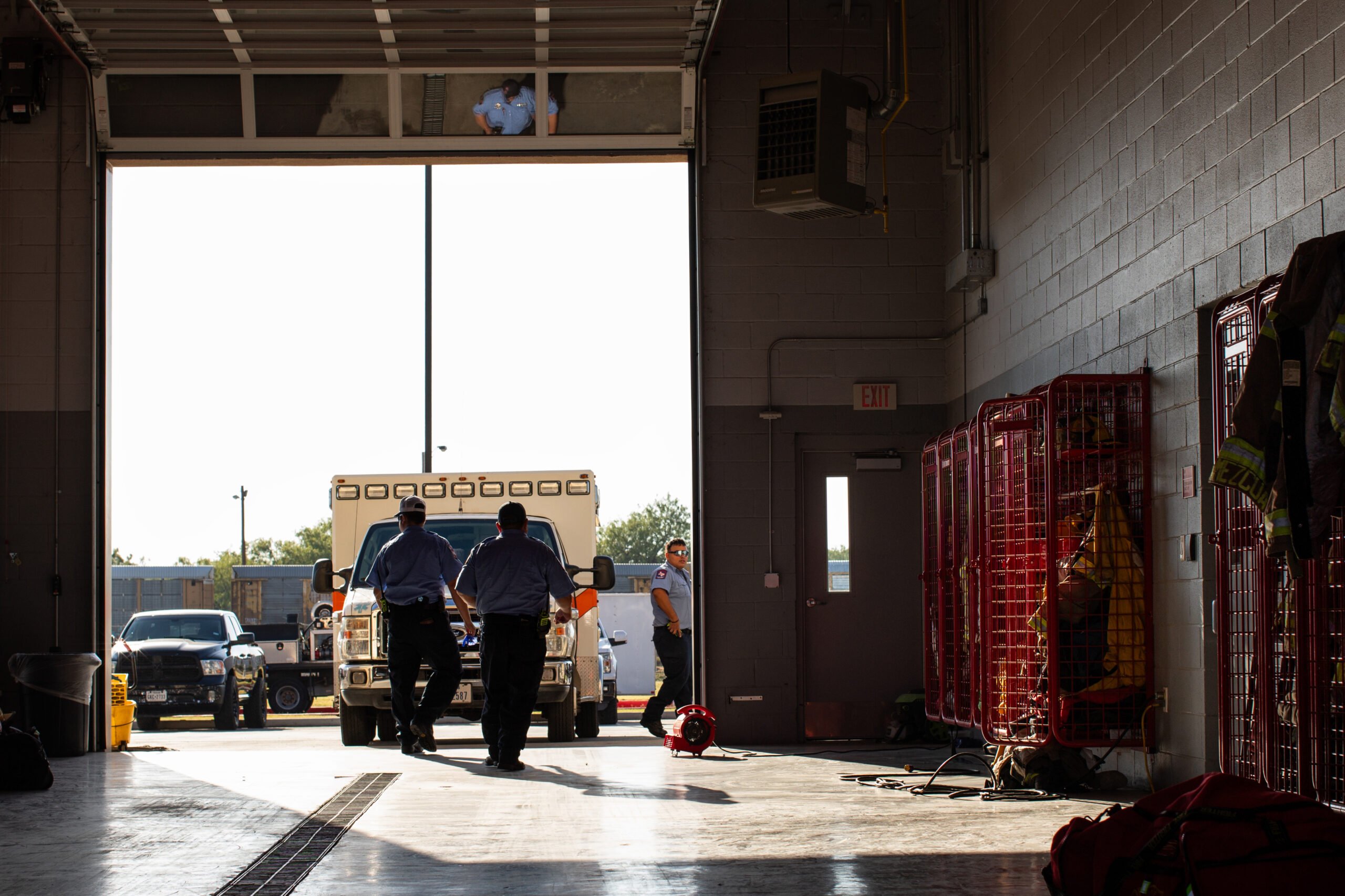 A photo showing Firefighter EMTs Rudy Castillon (left), Alfonso Garcia-ZuaZua and Israel Sanchez walking through the apparatus bay