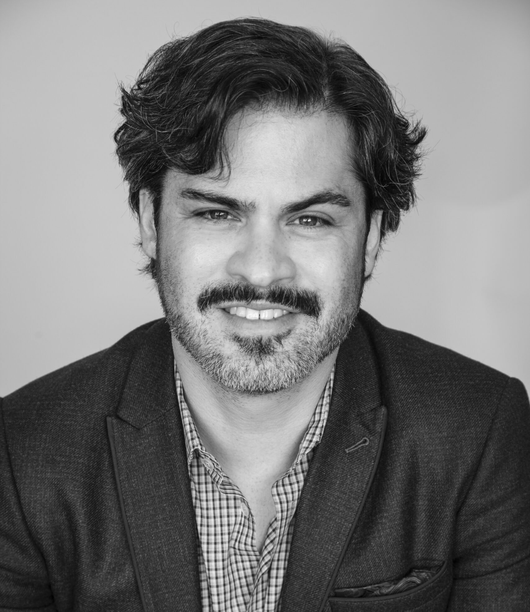 Ricardo Nuila smiles, wearing a suit jacket and button down.