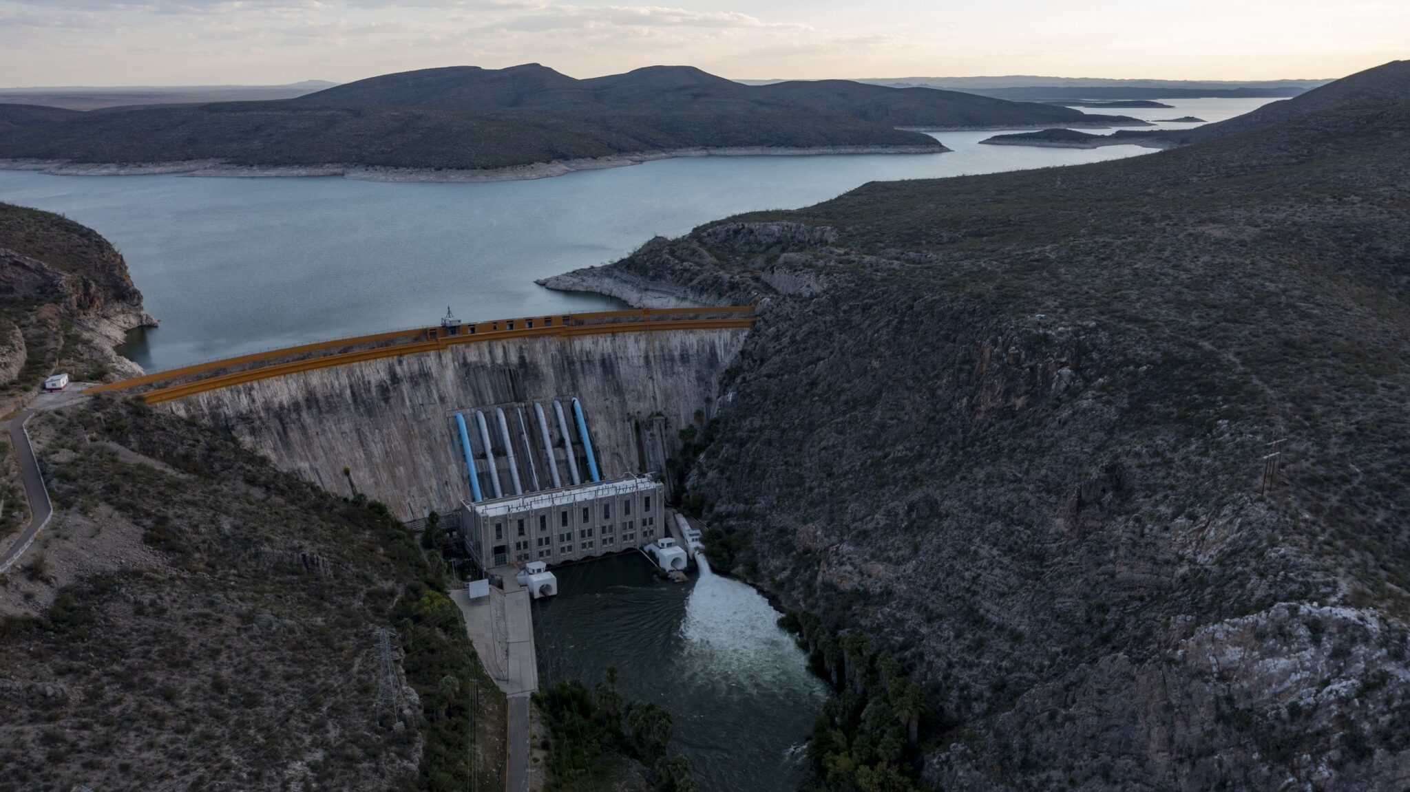 A dramatic overhead drone shot of a working dam at dusk.