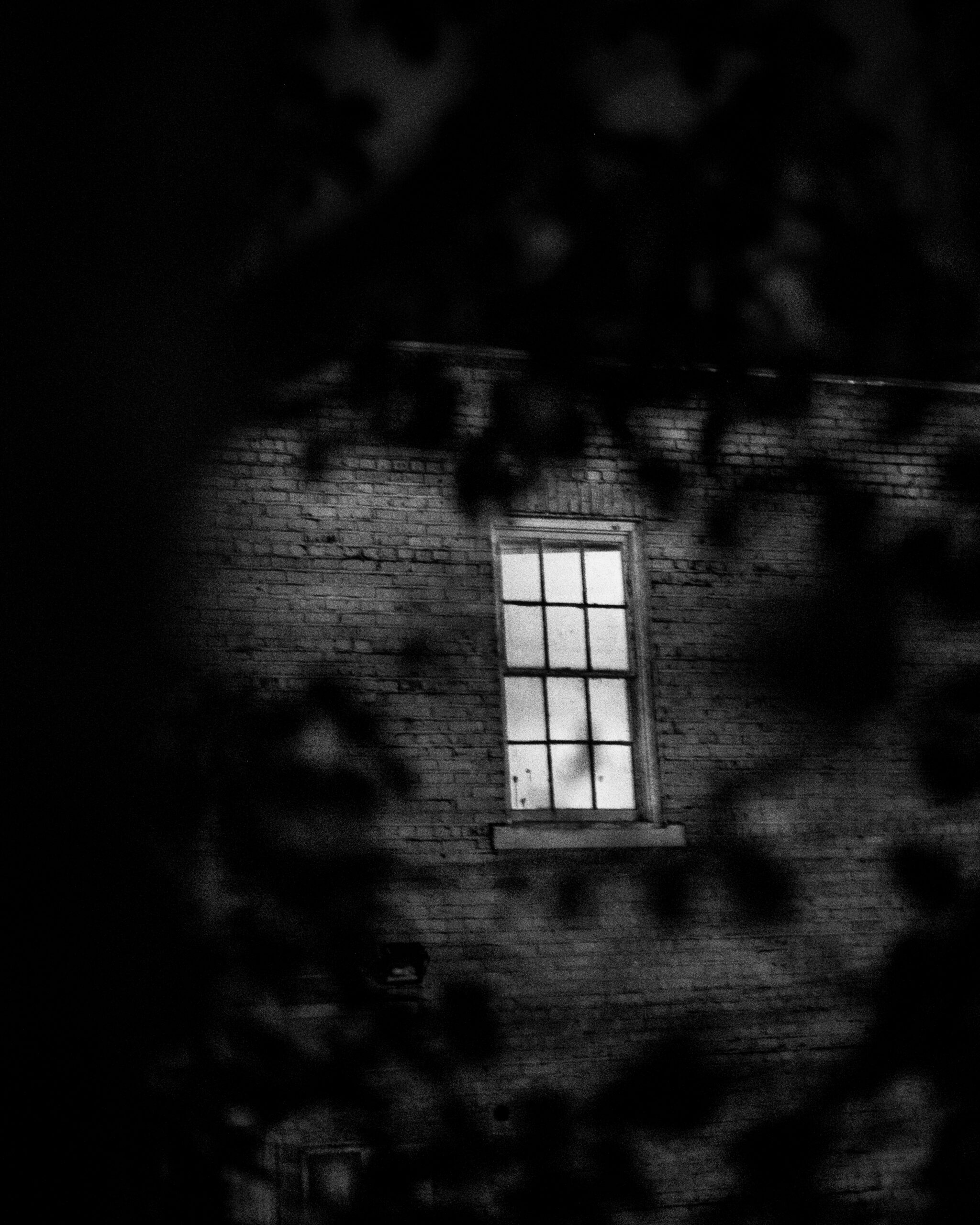 Light pours from the glass window, AGE of Central Texas Building, previously the Confederate Women’s Home in Austin, Texas, with a spooky feel to the black and white picture.