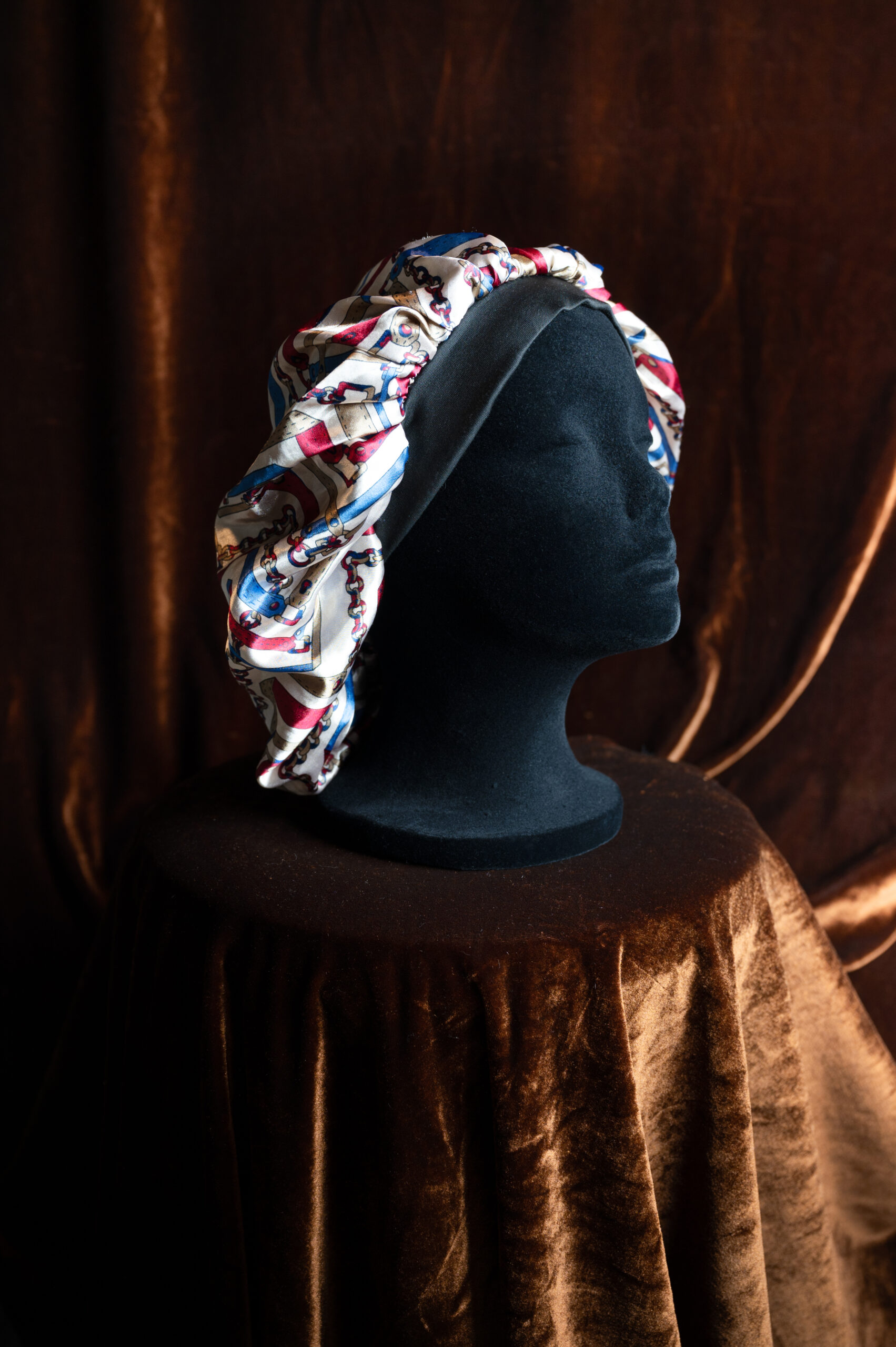 A colorful patterned bonnet on a mannequin head.