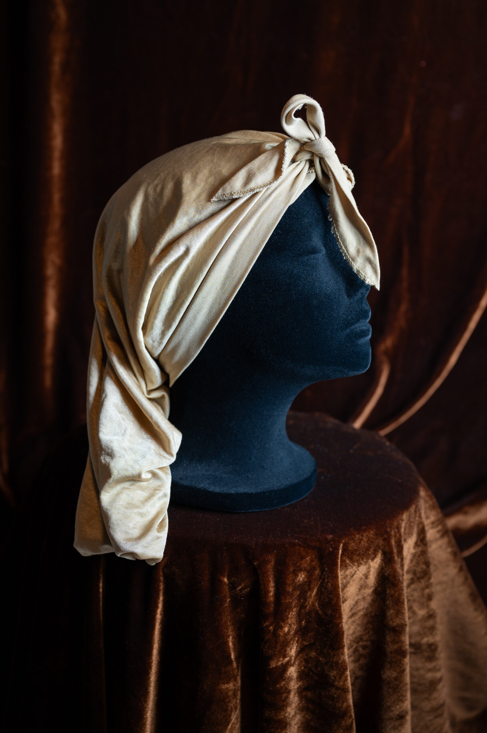A grey silk headwrap on a mannequin head.