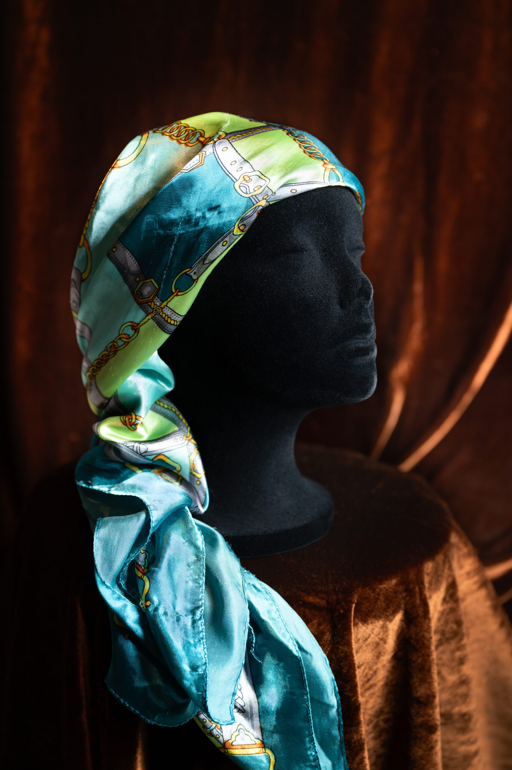A patterned, multicolor silk scarf on a mannequin head