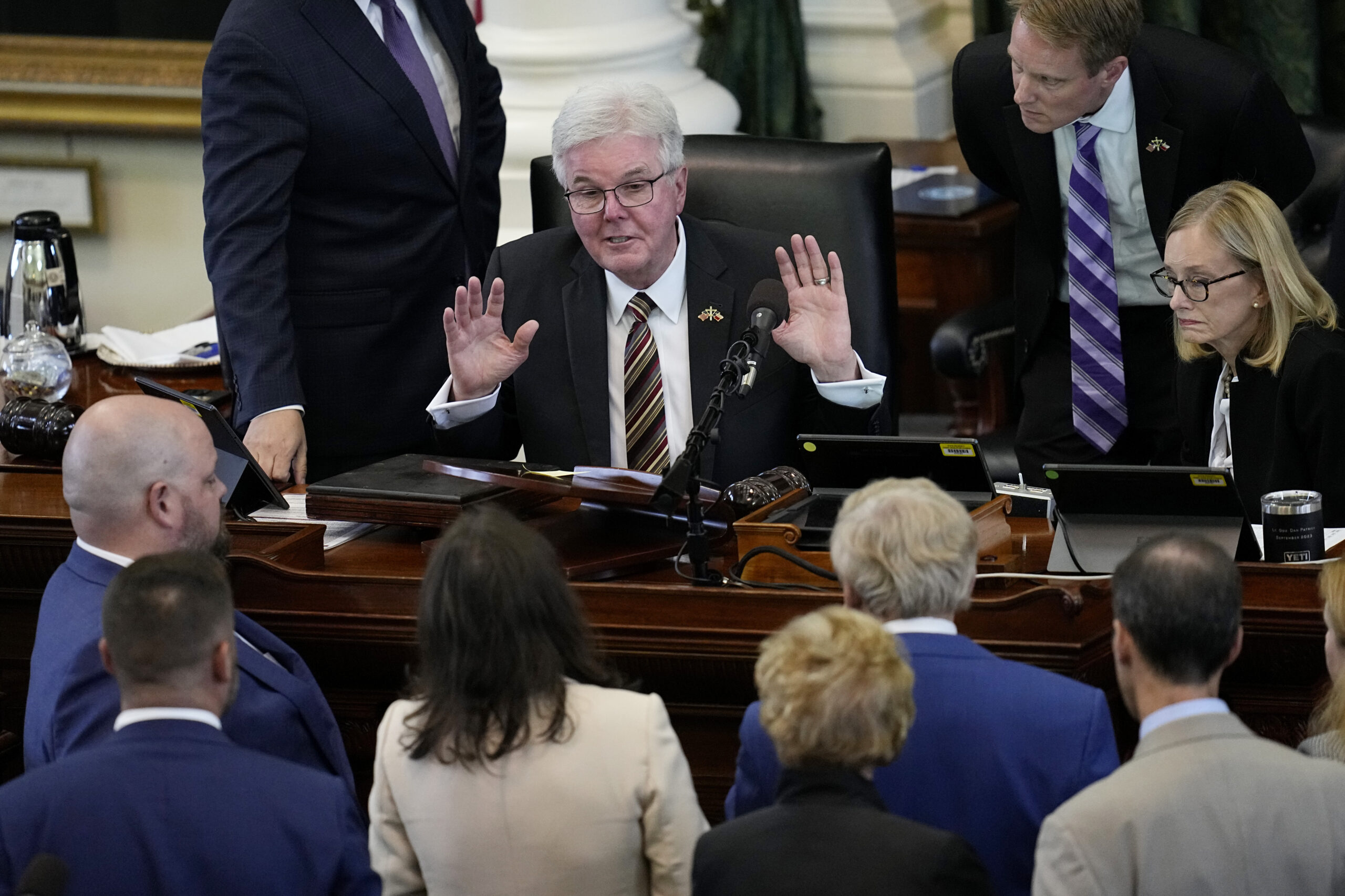 Texas Lt. Gov. Dan Patrick, center, throws up his hands as he talks with defense and prosecution counsel during the impeachment trial for suspended Texas Attorney General Ken Paxton in the Senate Chamber at the Texas Capitol, Thursday, Sept. 14, 2023, in Austin, Texas. (AP Photo/Eric Gay)
