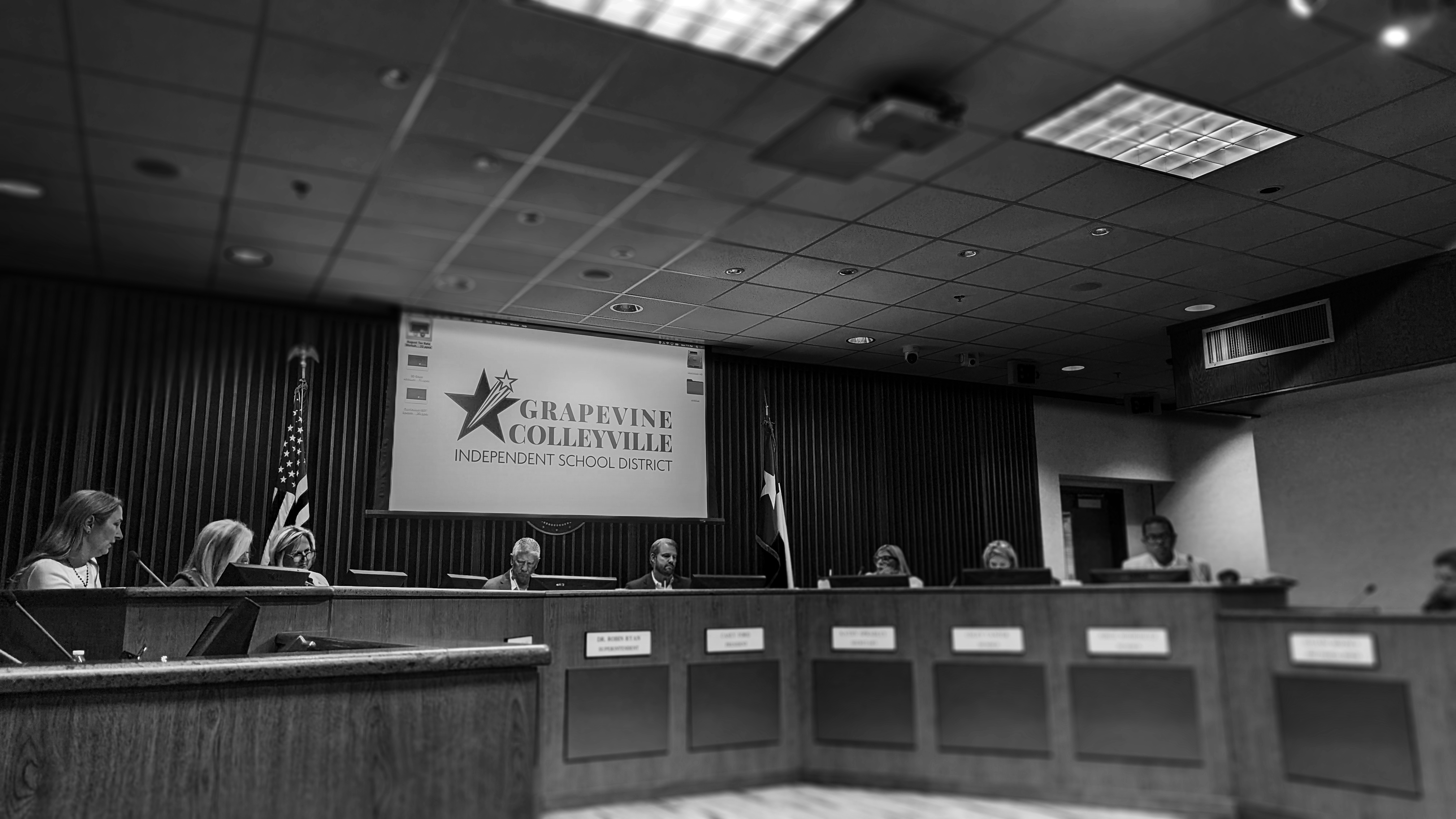 A black and white photo of the trustees' board room. About 9 of the members are present.