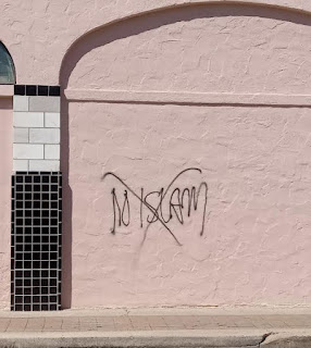 Graffiti on a pink exterior wall with the words "No Islam" with an "X" through it