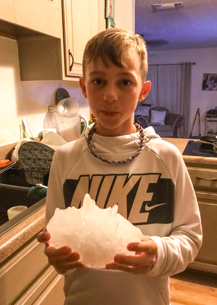 Evan Craft holds a massive hailstone. He has a Nike shirt on. 
