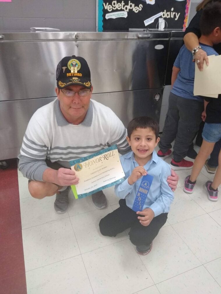 Timothy and his dad, also named Timothy Murray, display a copy of an honor roll certificate.